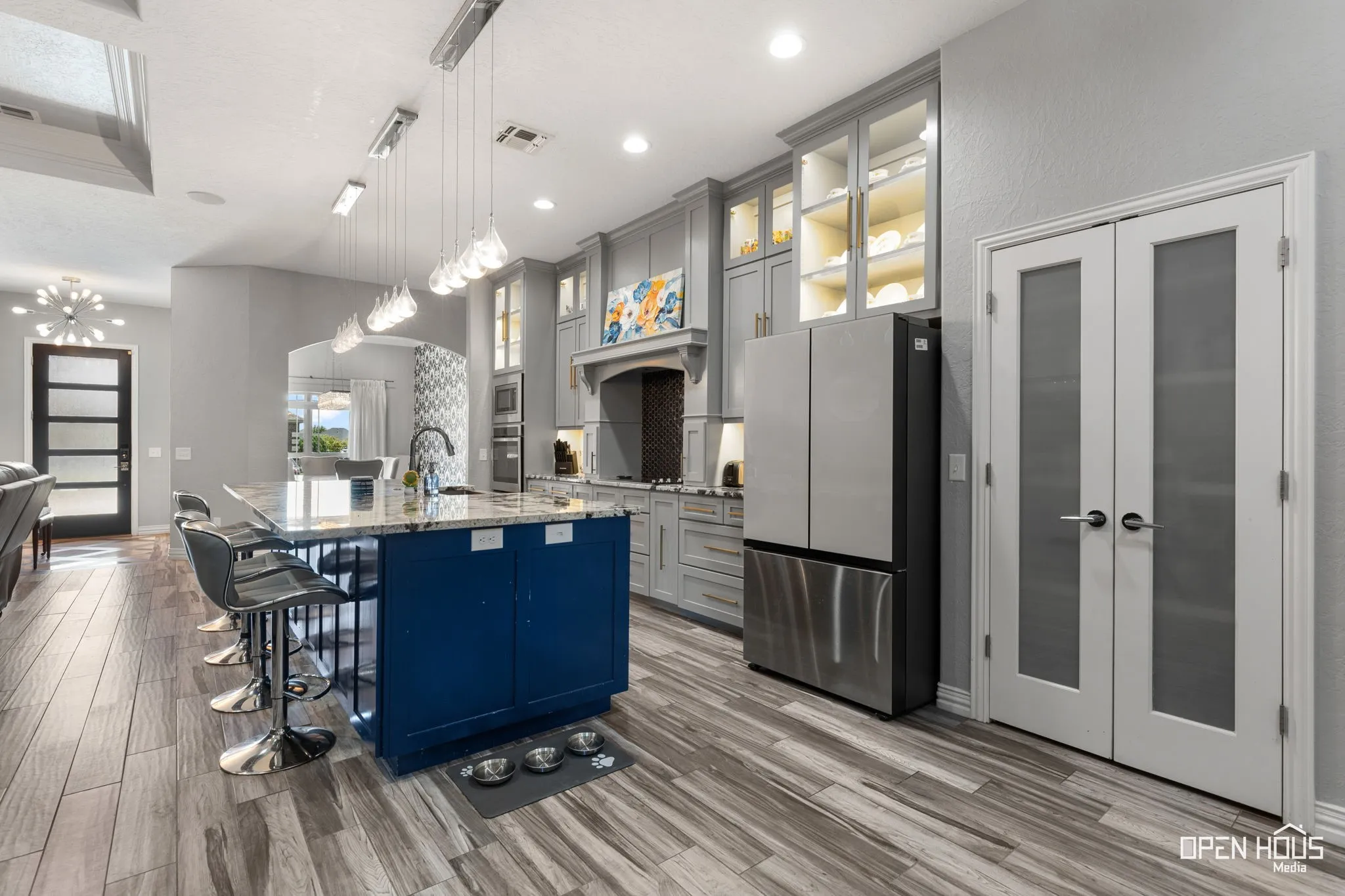 Spacious kitchen featuring an expansive center island with seating, pendant lighting, stainless steel appliances, and tile flooring