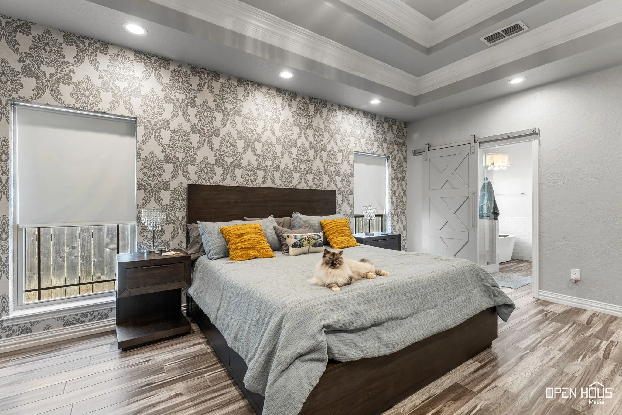Tile flooring, accent wall with patterned wallpaper, recessed lighting, tray ceiling, and a barn door