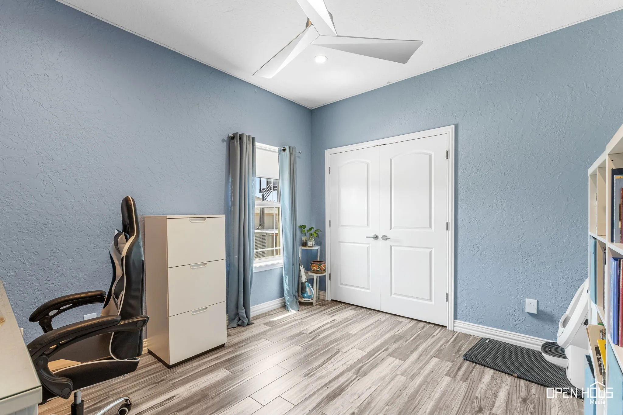 Tile flooring, light blue wall finish, white ceiling fan, double panel doors, and a window with curtains