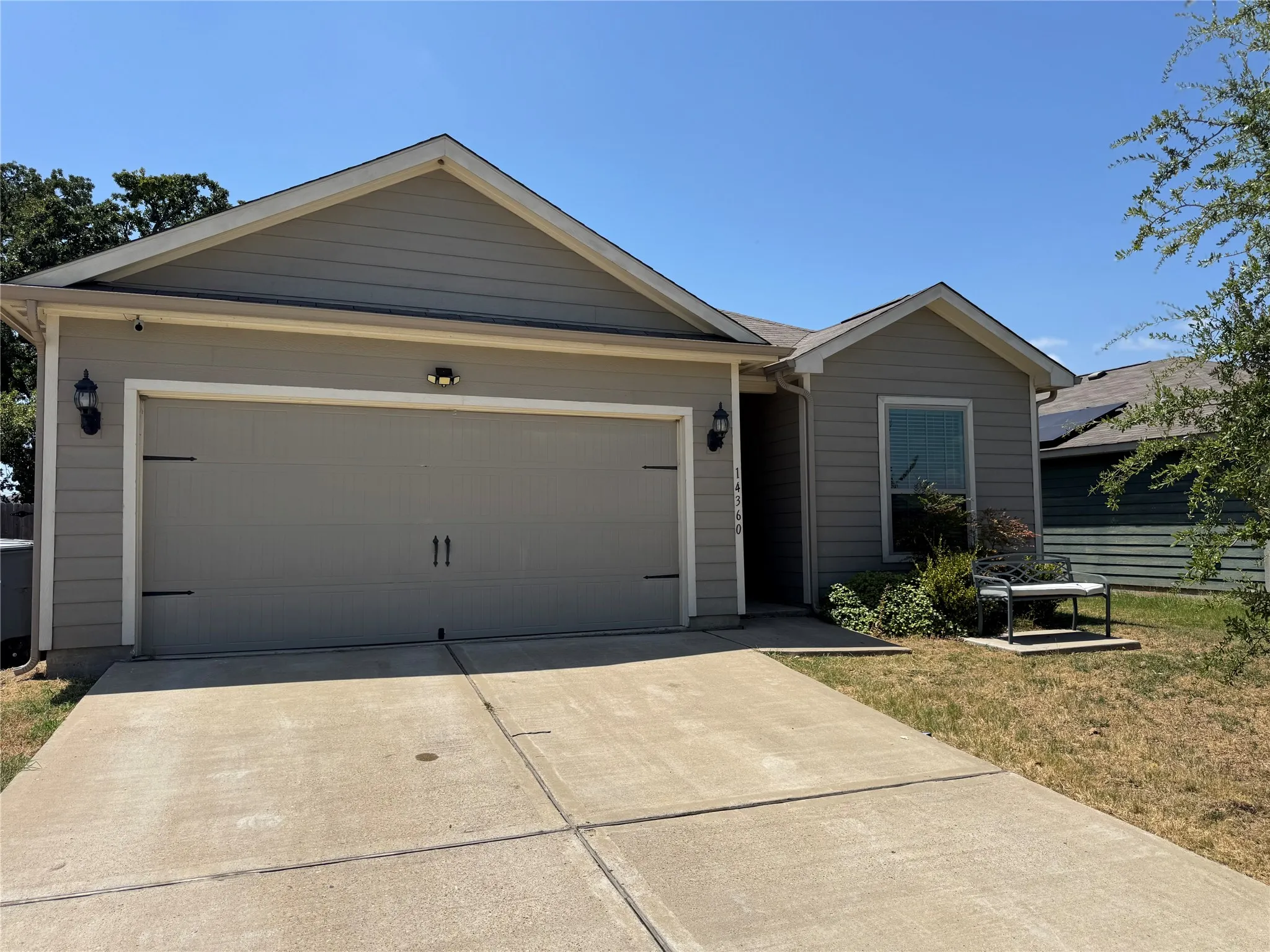 Attached garage with carriage-style door, exterior light fixtures, and a concrete driveway