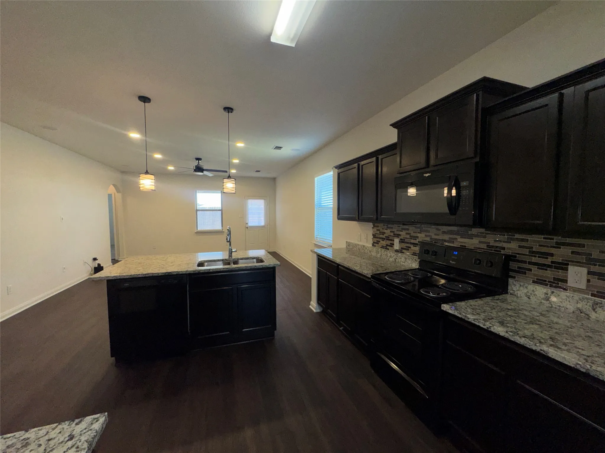 Kitchen featuring dark wood-finish cabinetry, granite countertops, and a mosaic tile backsplash