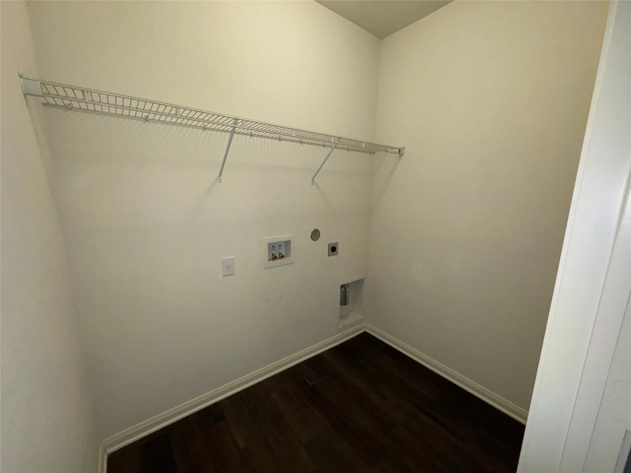 Utility room featuring wire shelving, wall hookups, and wood-finish flooring
