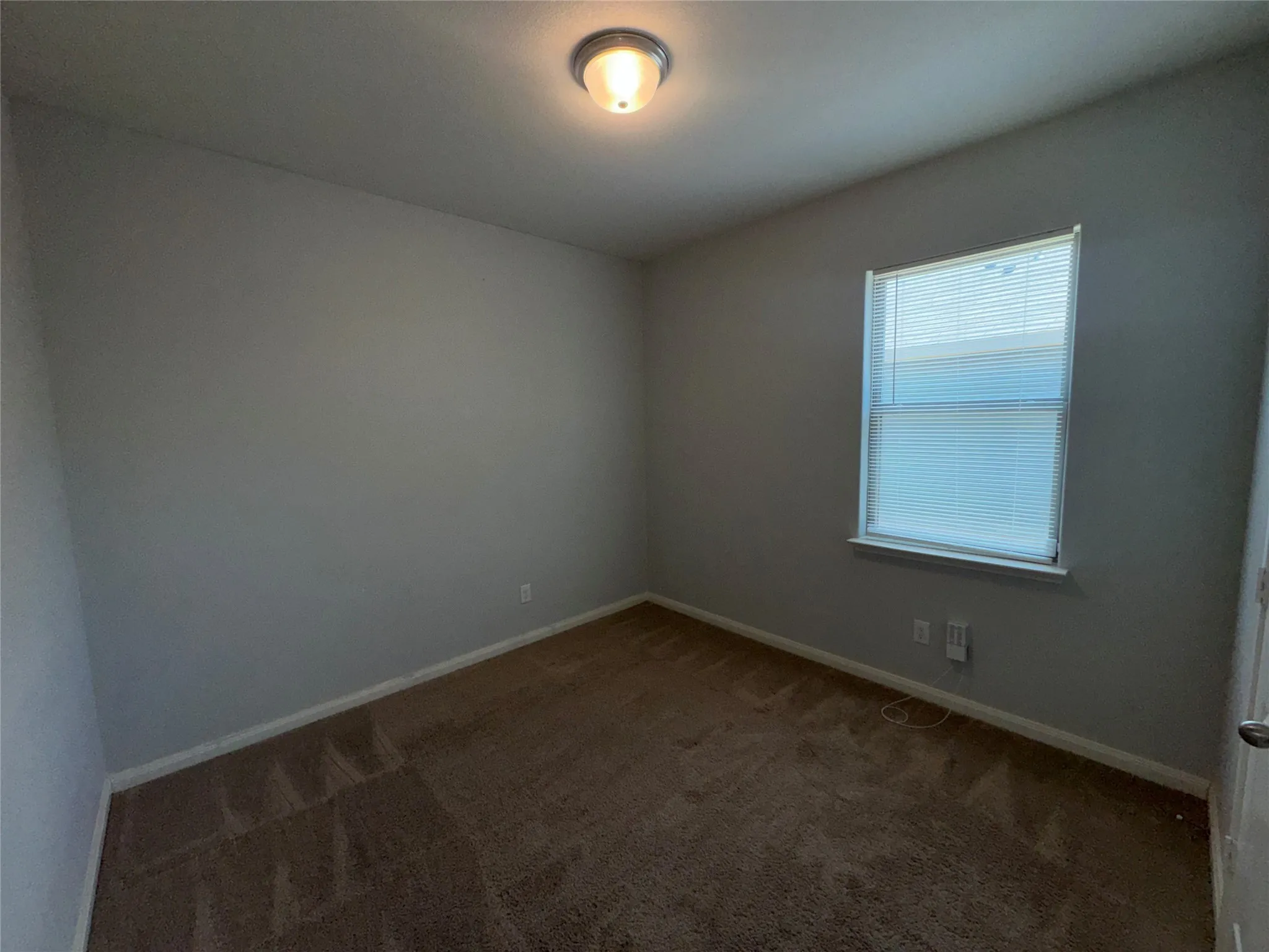 Bright secondary bedroom featuring neutral wall finishes, wood-finish carpeting, a single-hung window with natural light, and recessed ceiling lighting