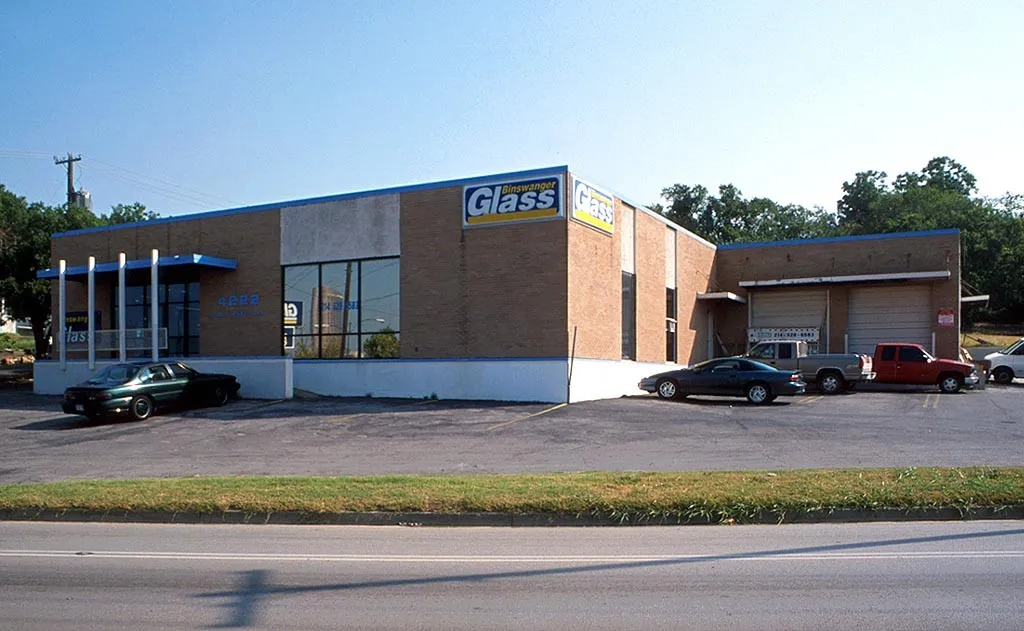 Brick exterior building with expansive front windows, a blue awning, and multiple overhead doors