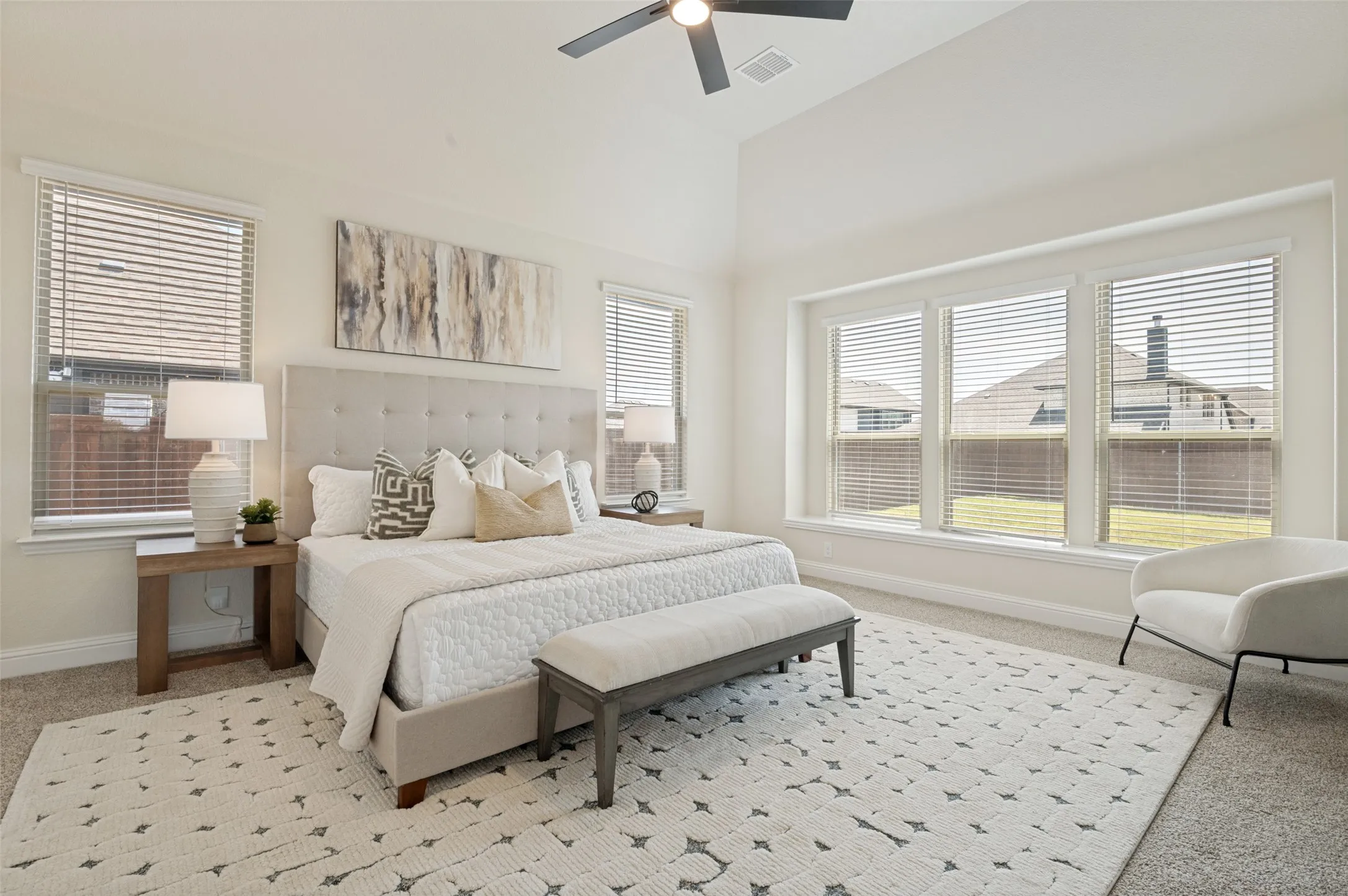 Vaulted ceiling, ceiling fan, expansive windows with horizontal blinds, carpeted flooring, and a built-in window ledge