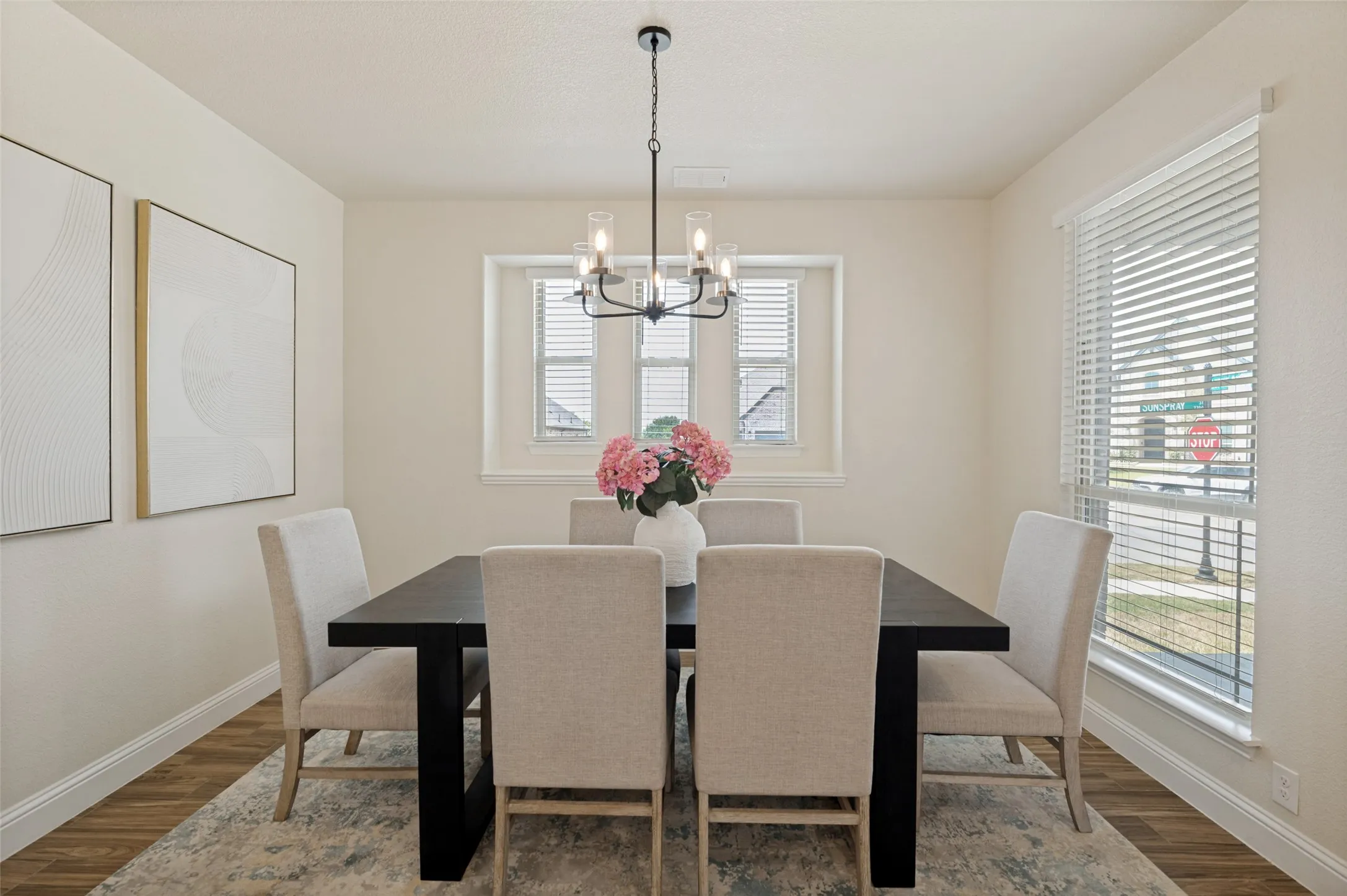 Dining area featuring wood-finish flooring, multiple windows with blinds, and a multi-bulb chandelier