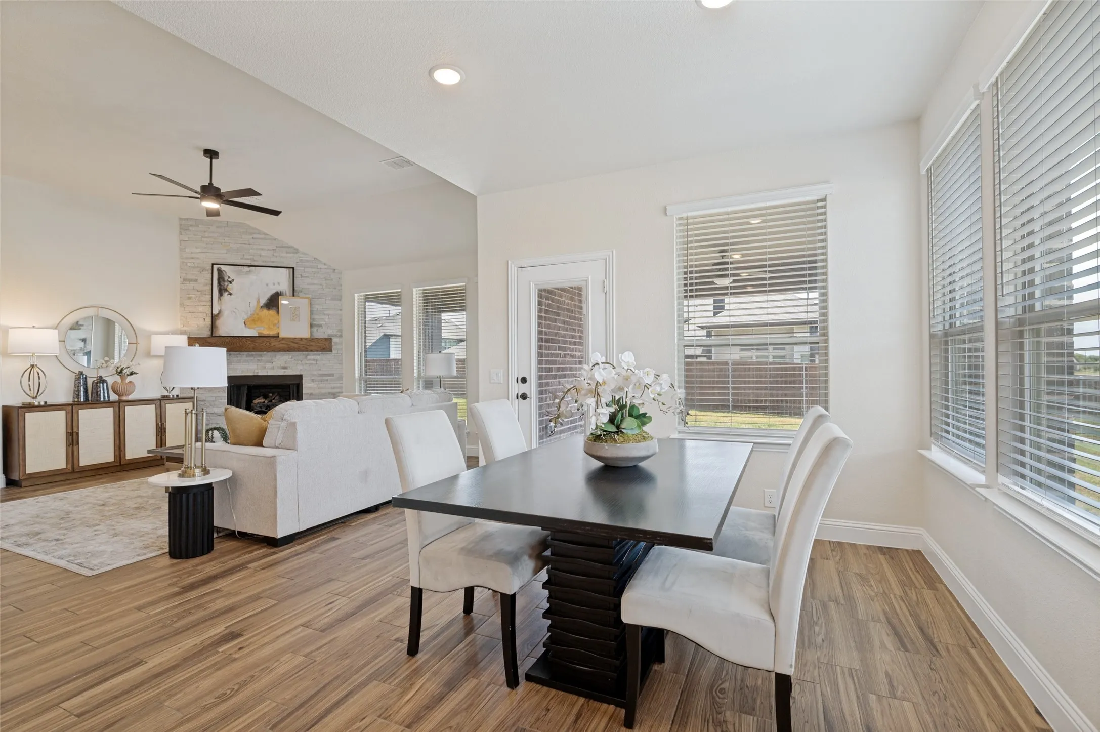 Wood-finish flooring throughout, vaulted ceiling, recessed lighting, and a stone-clad fireplace with a wood mantel