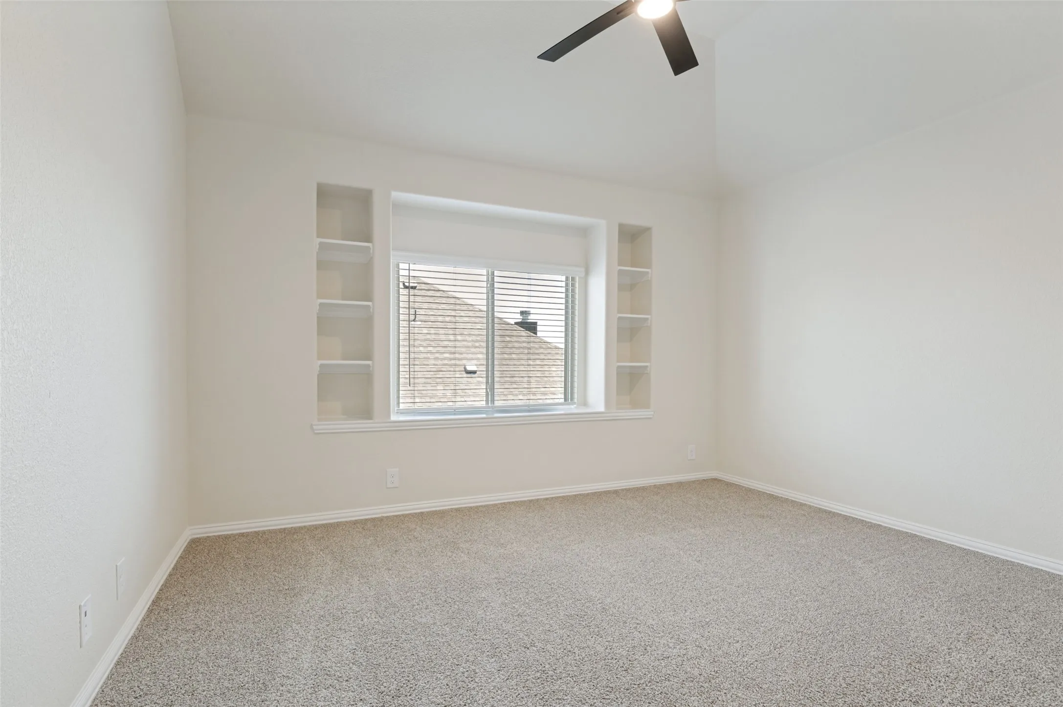 Vaulted ceiling, ceiling fan, built-in shelving, window with blinds, carpeted flooring