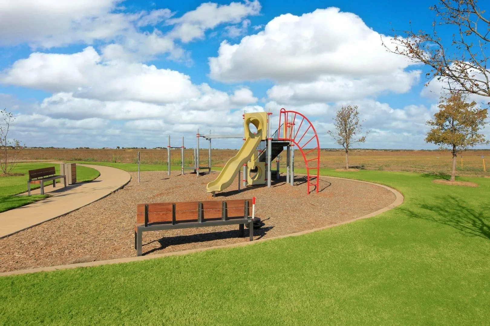 Recreational area featuring a playground structure with slide, climbing elements, and bark mulch surfacing