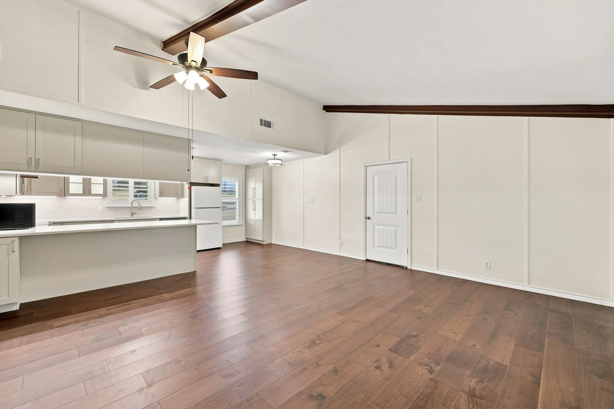 Vaulted ceiling with exposed wood beams and a ceiling fan