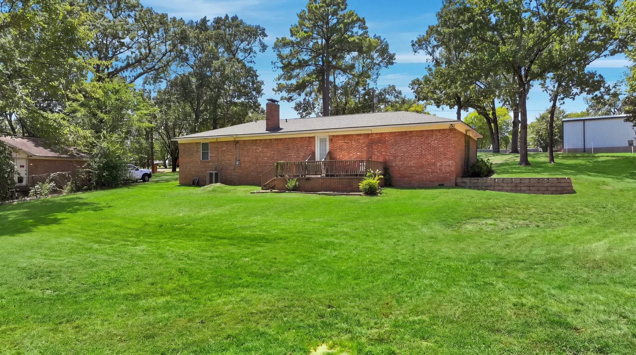 Expansive green lawn with mature trees and a brick-sided residence