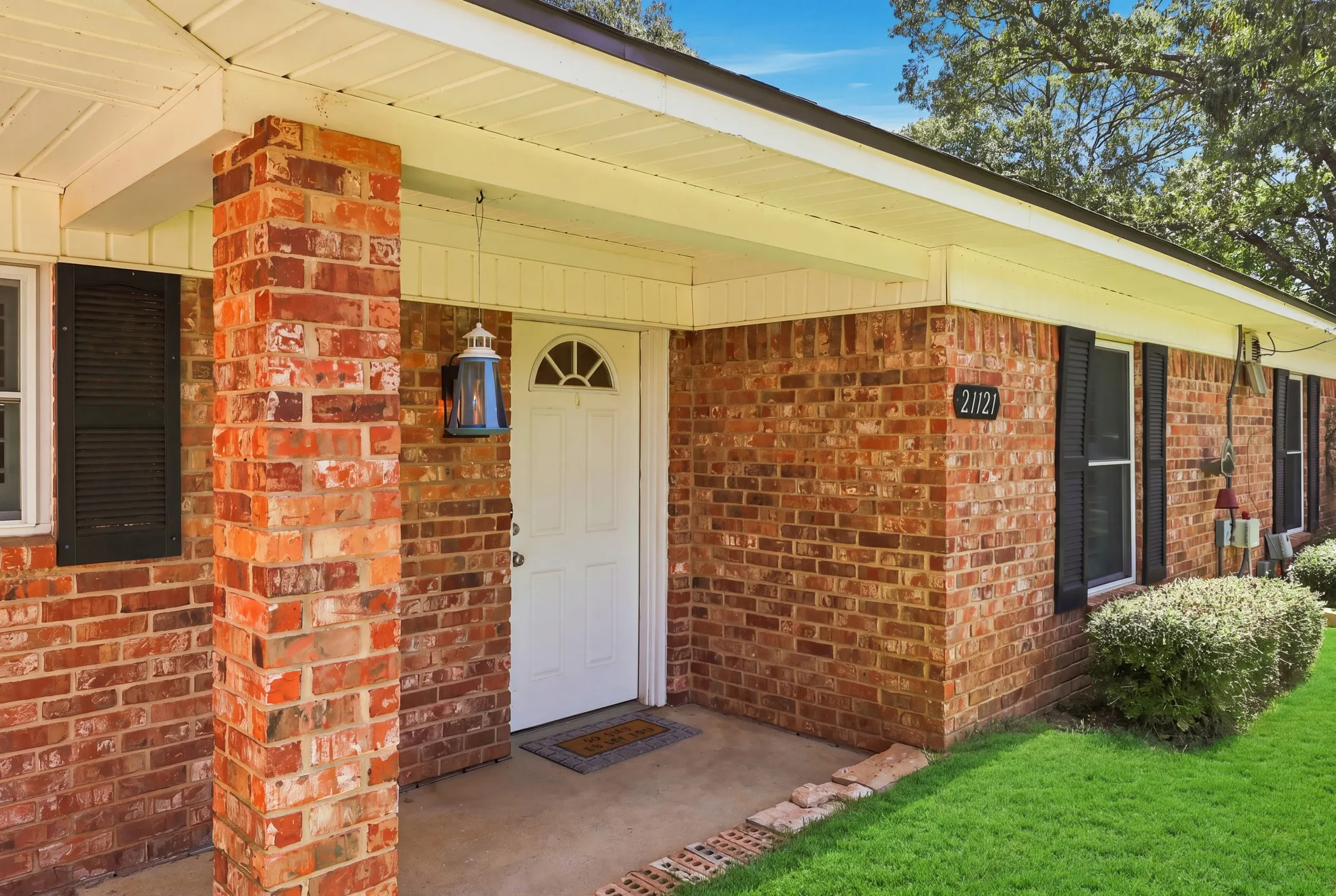 Brick exterior with white trim, covered front entry, and multiple windows with dark shutters