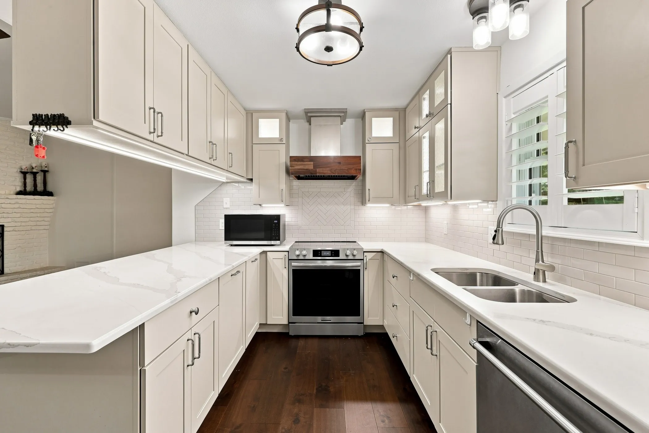 U-shaped kitchen with light cabinetry, white countertops, stainless steel appliances, and dark wood-finish flooring