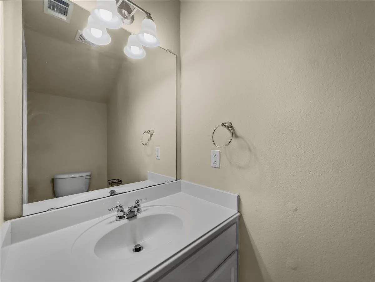 White vanity with an integrated sink, chrome faucet, and expansive wall-mounted mirror