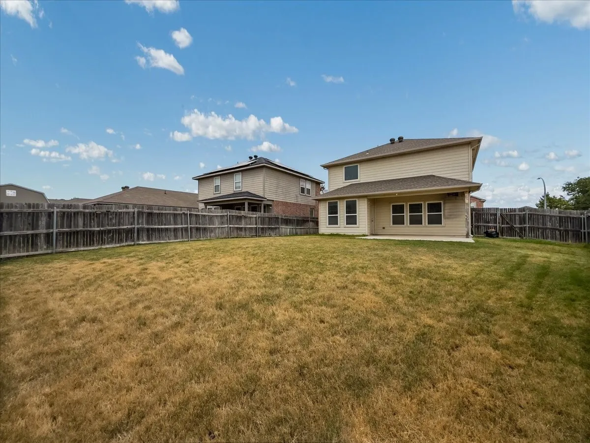 Expansive backyard space with perimeter fencing and a concrete patio