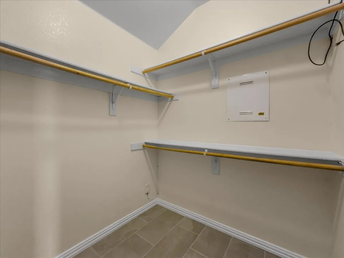 Walk-in closet with built-in shelving, hanging rods, and tile flooring
