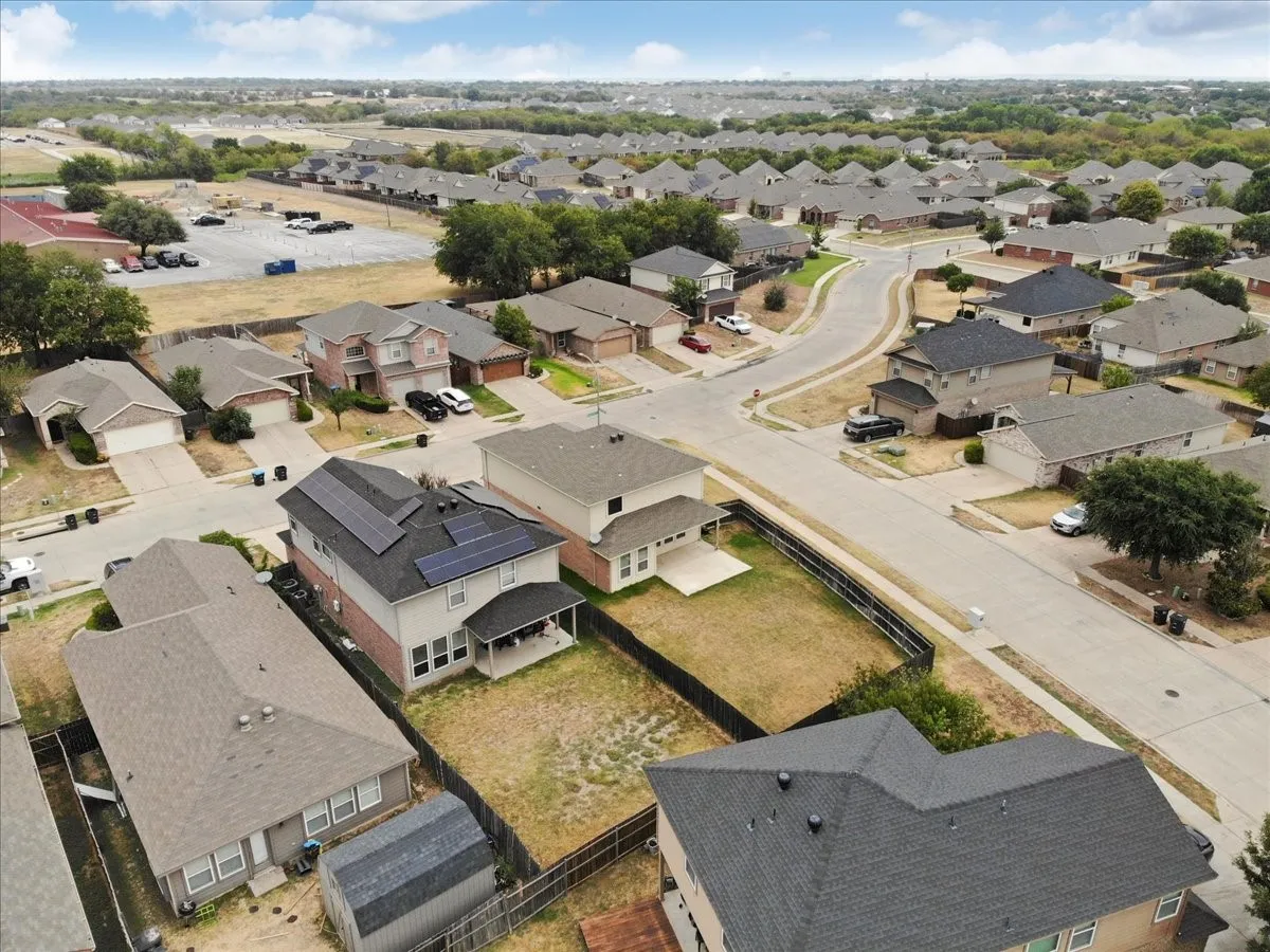 Two-story residence with a covered patio, solar panels, and a fenced backyard