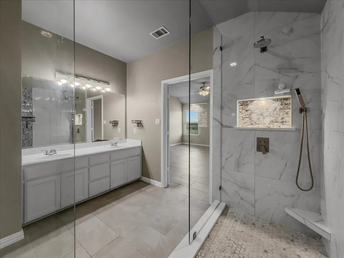Dual-sink vanity with light gray cabinetry and an expansive mirror
