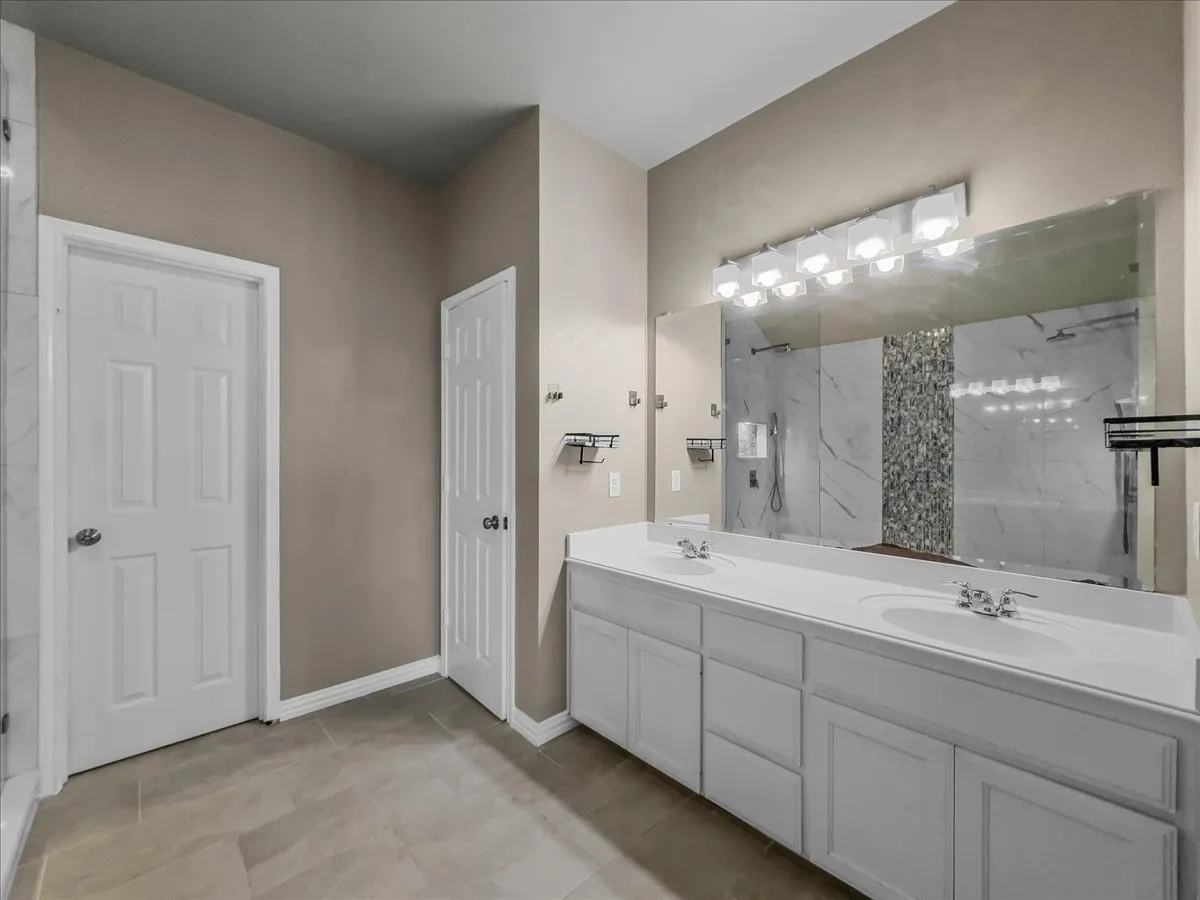 Dual vanity with integrated sinks, full-width mirror, and multi-bulb light fixture