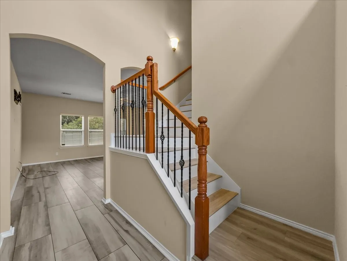 Staircase featuring wood railings and wrought iron balusters