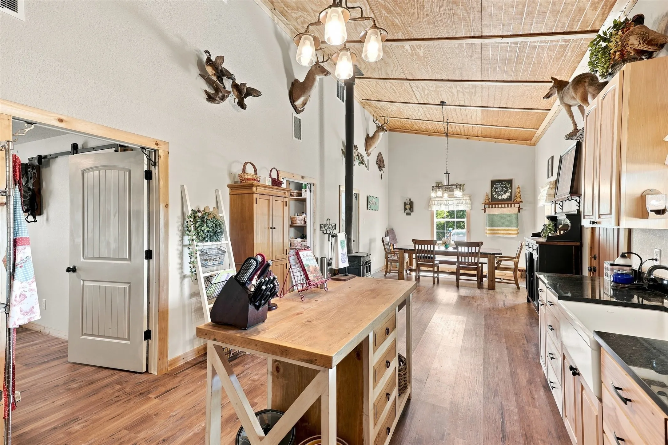 Vaulted wood-finish ceiling, wood-finish flooring, kitchen island with wood countertop, kitchen with built-in cabinetry, and dining area with chandelier