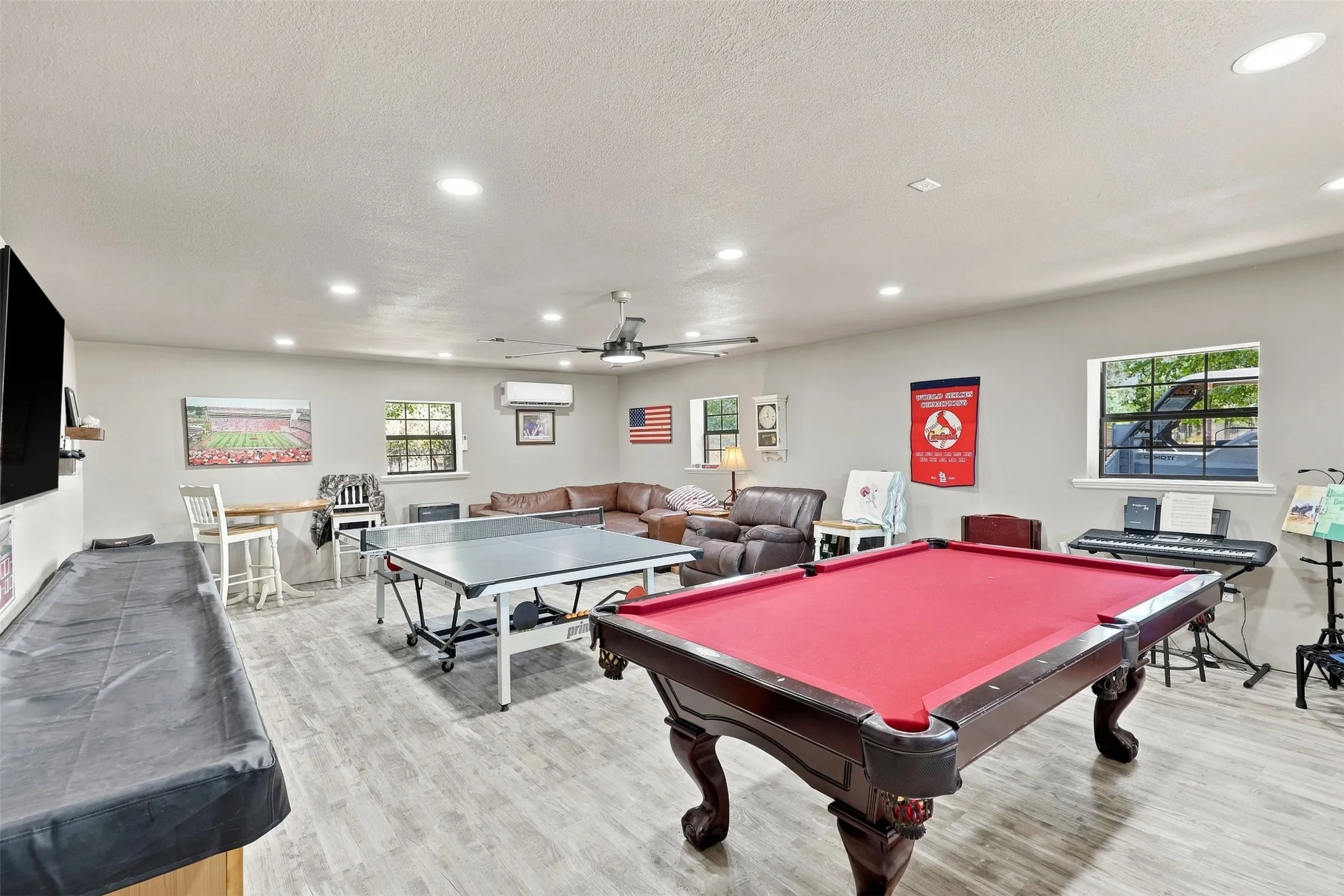 Spacious room featuring wood-finish flooring, recessed lighting, ceiling fan, and multiple windows