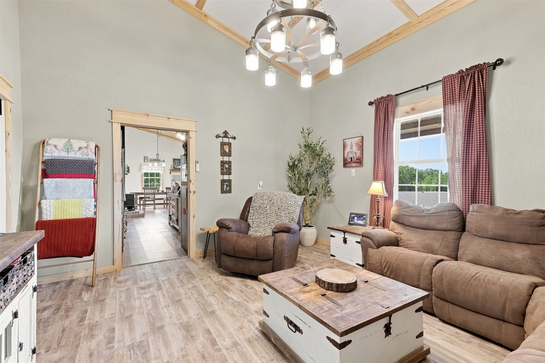 Vaulted ceiling with exposed wood beams, wood-finish flooring, and a decorative chandelier