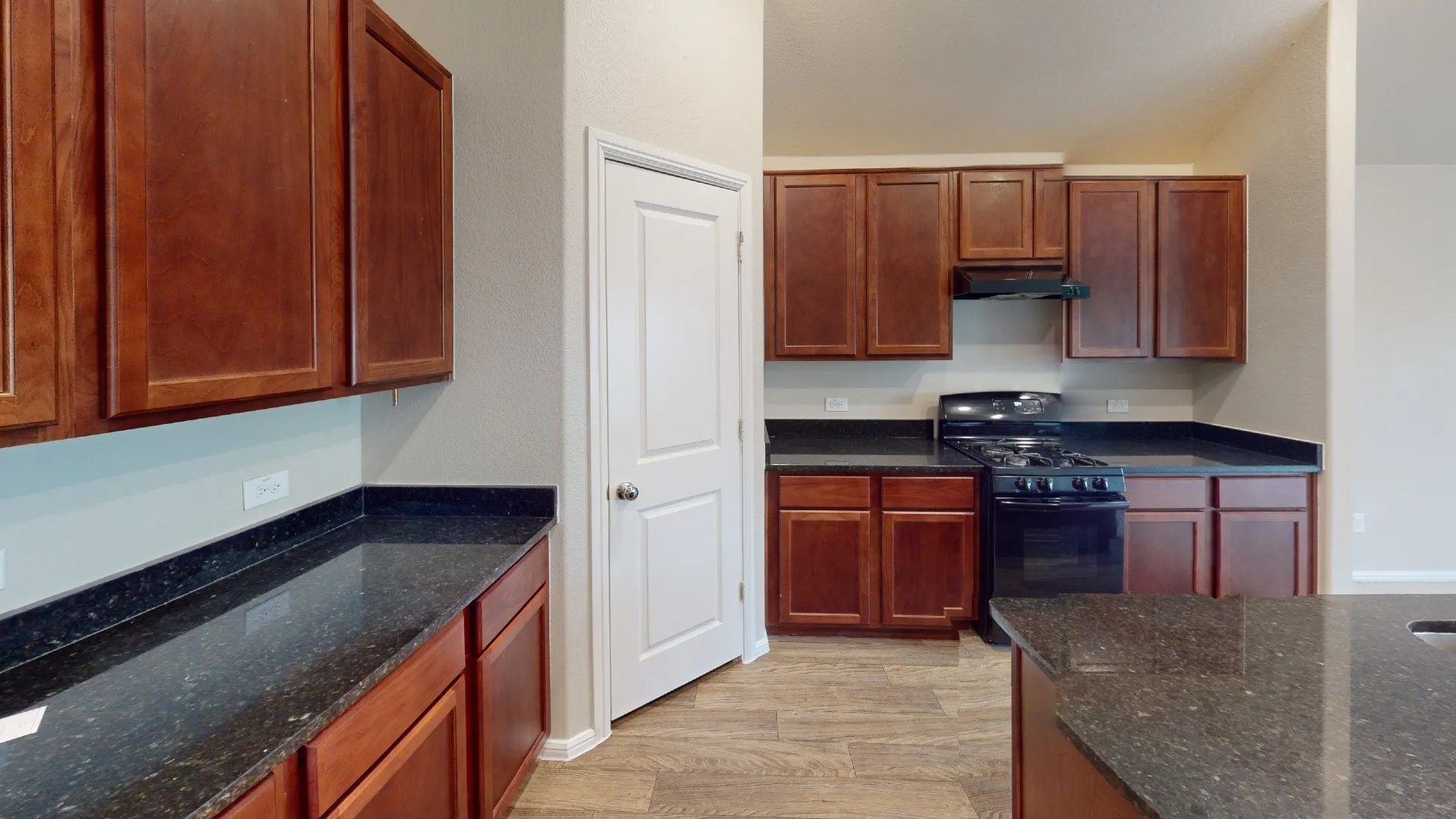 Kitchen featuring wood-finish cabinetry, dark countertops, a gas range, and wood-finish flooring
