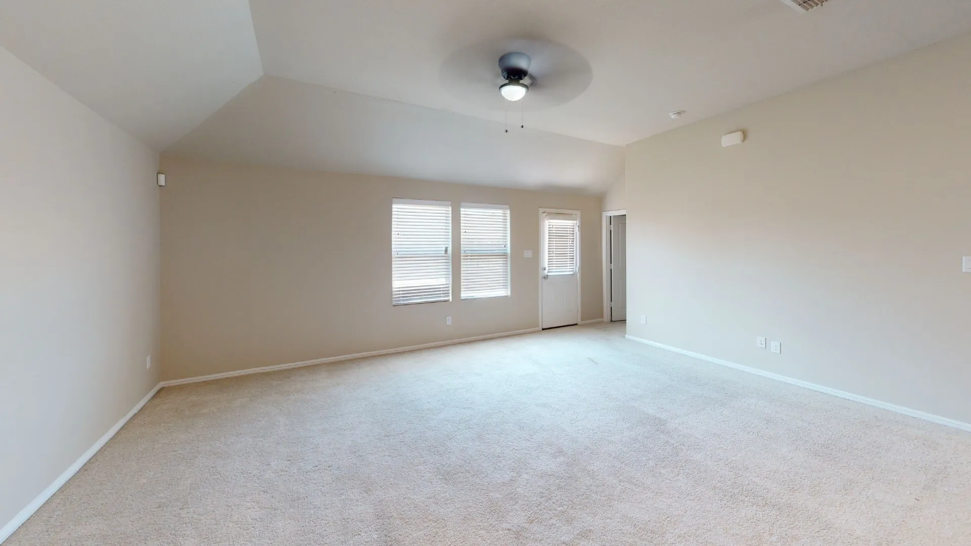 Vaulted ceilings, neutral carpeting, and a ceiling fan with light fixture