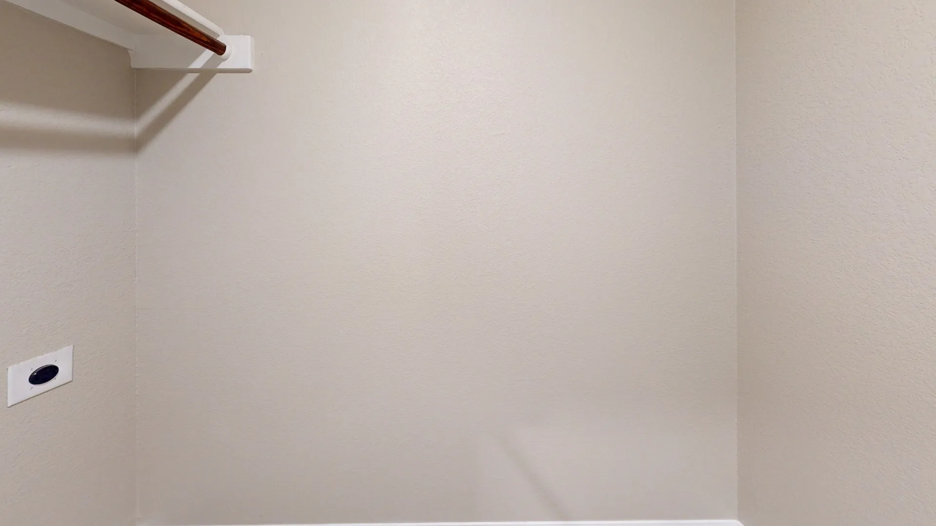 Storage area featuring a wood-finish hanging rod and a wall-mounted shelf
