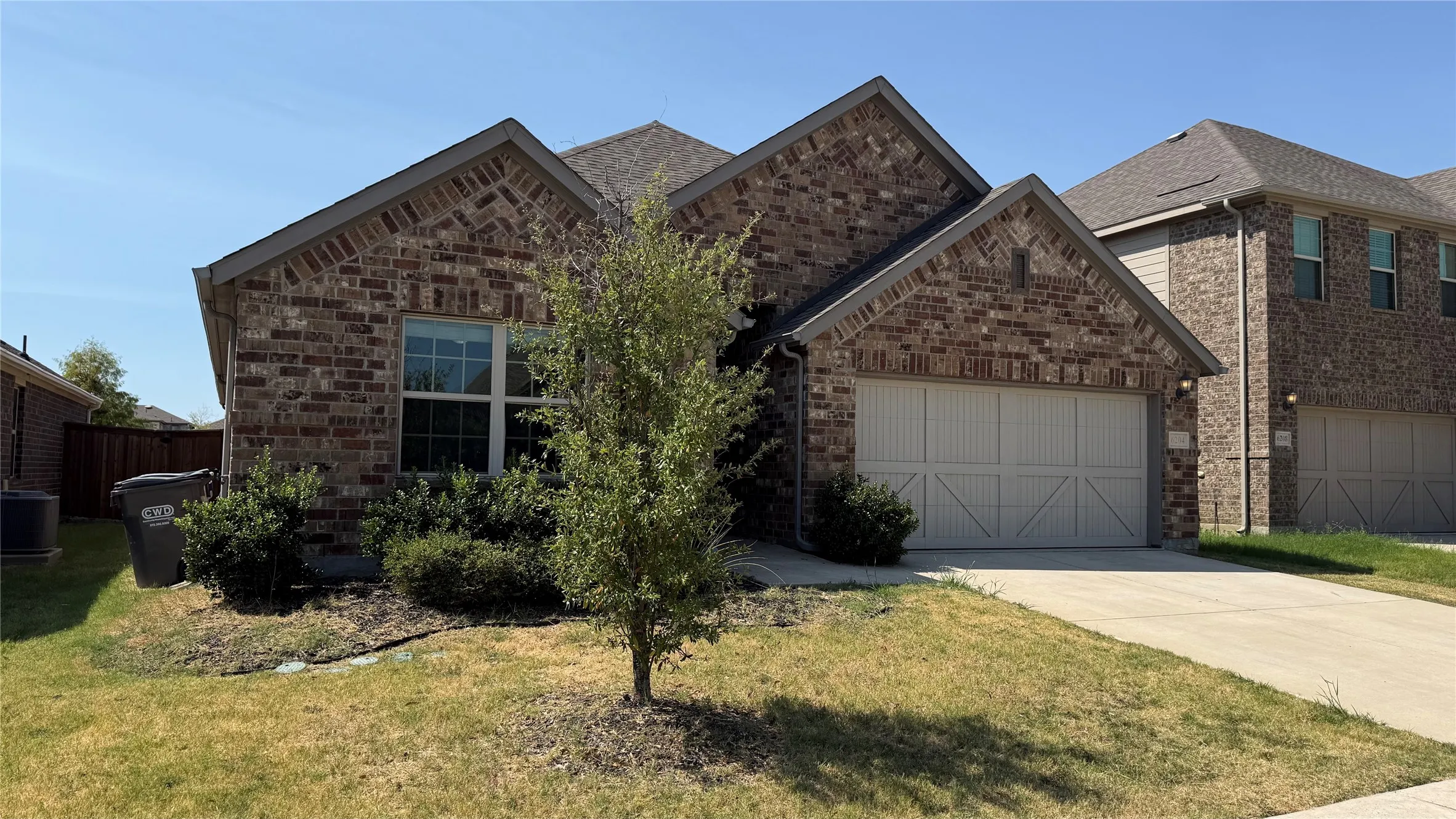 Brick exterior with a gabled roofline, front-facing garage with decorative doors, and a concrete driveway