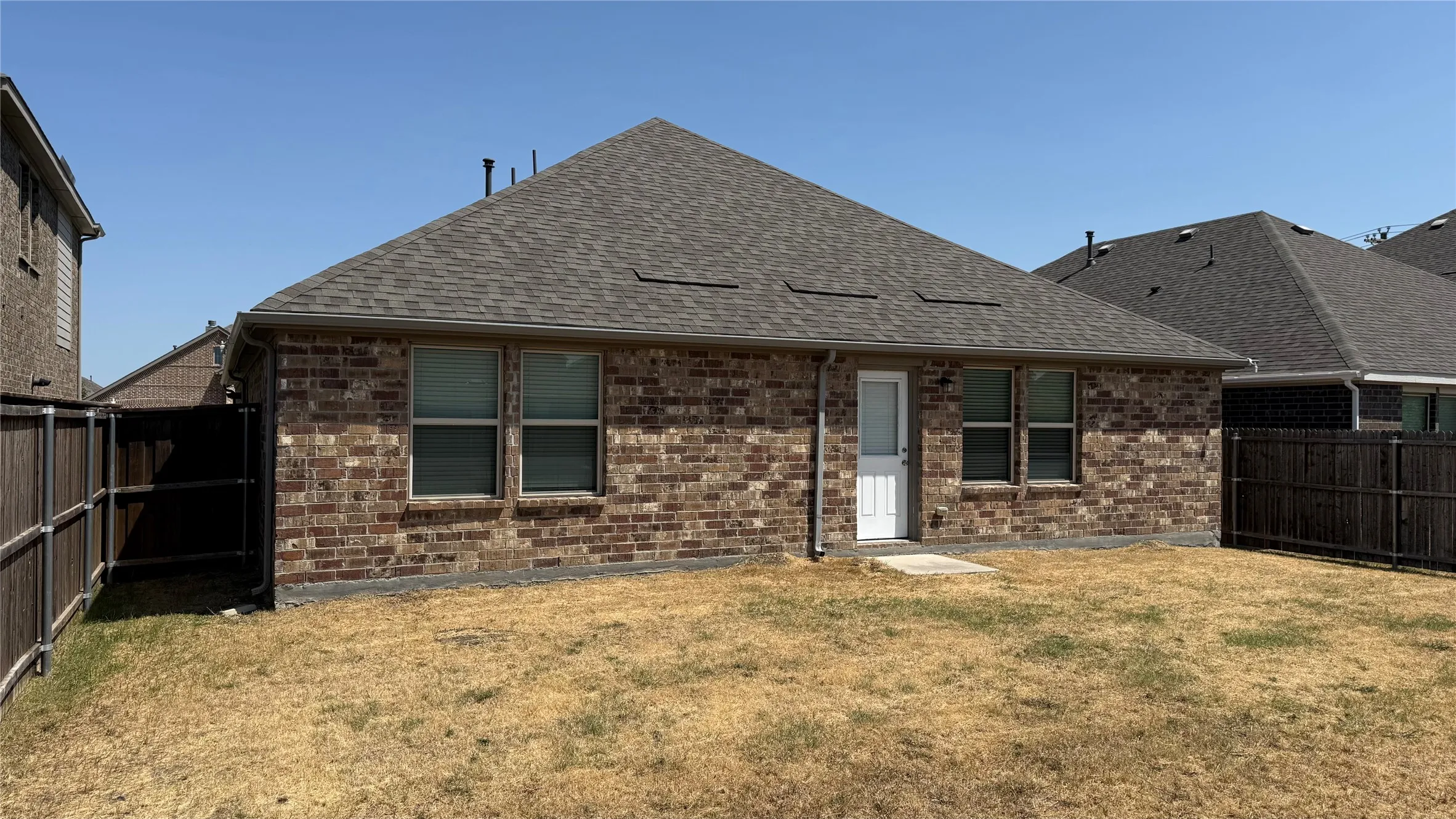 Brick exterior with a gabled roofline, front-facing garage with decorative doors, and a concrete driveway