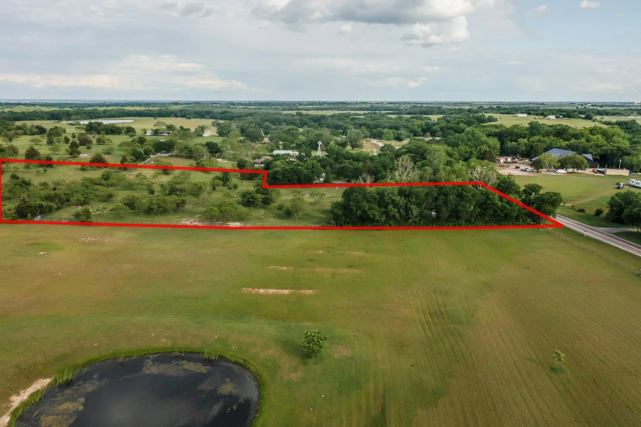 Expansive open land with mature trees and a natural pond