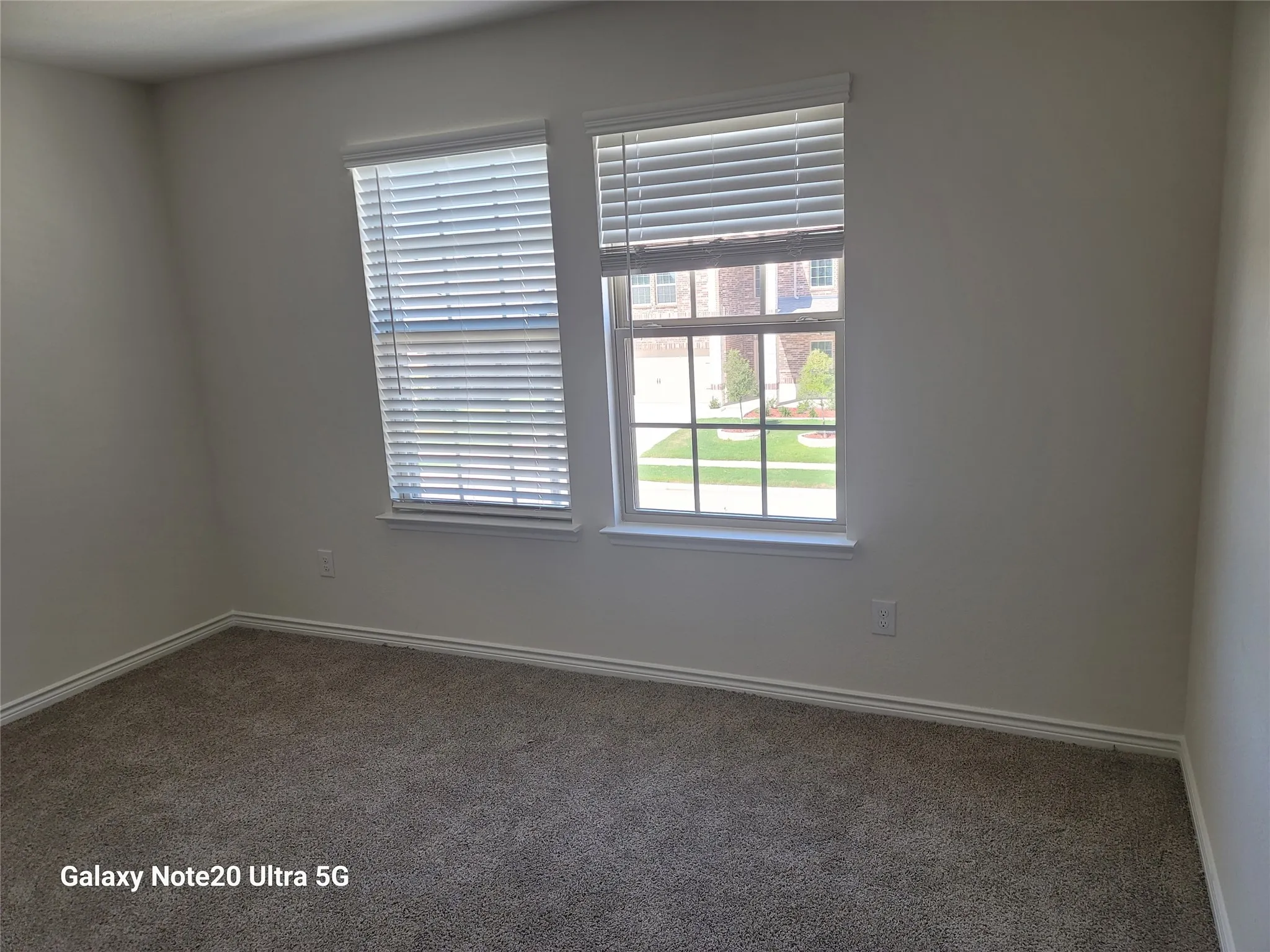Neutral-toned walls, two windows with blinds, and carpeting