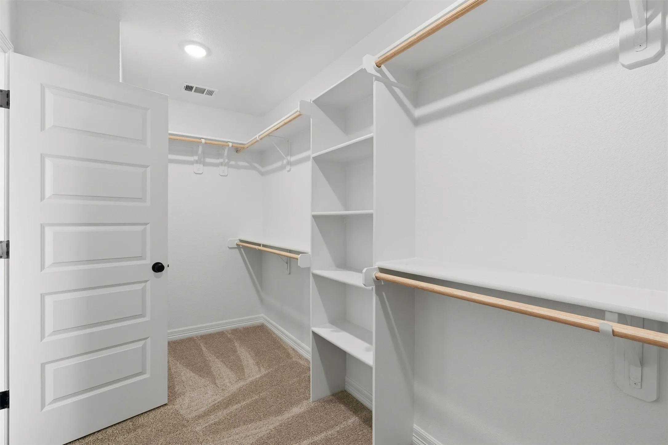 Walk-in closet with integrated shelving, multiple hanging rods, and recessed lighting