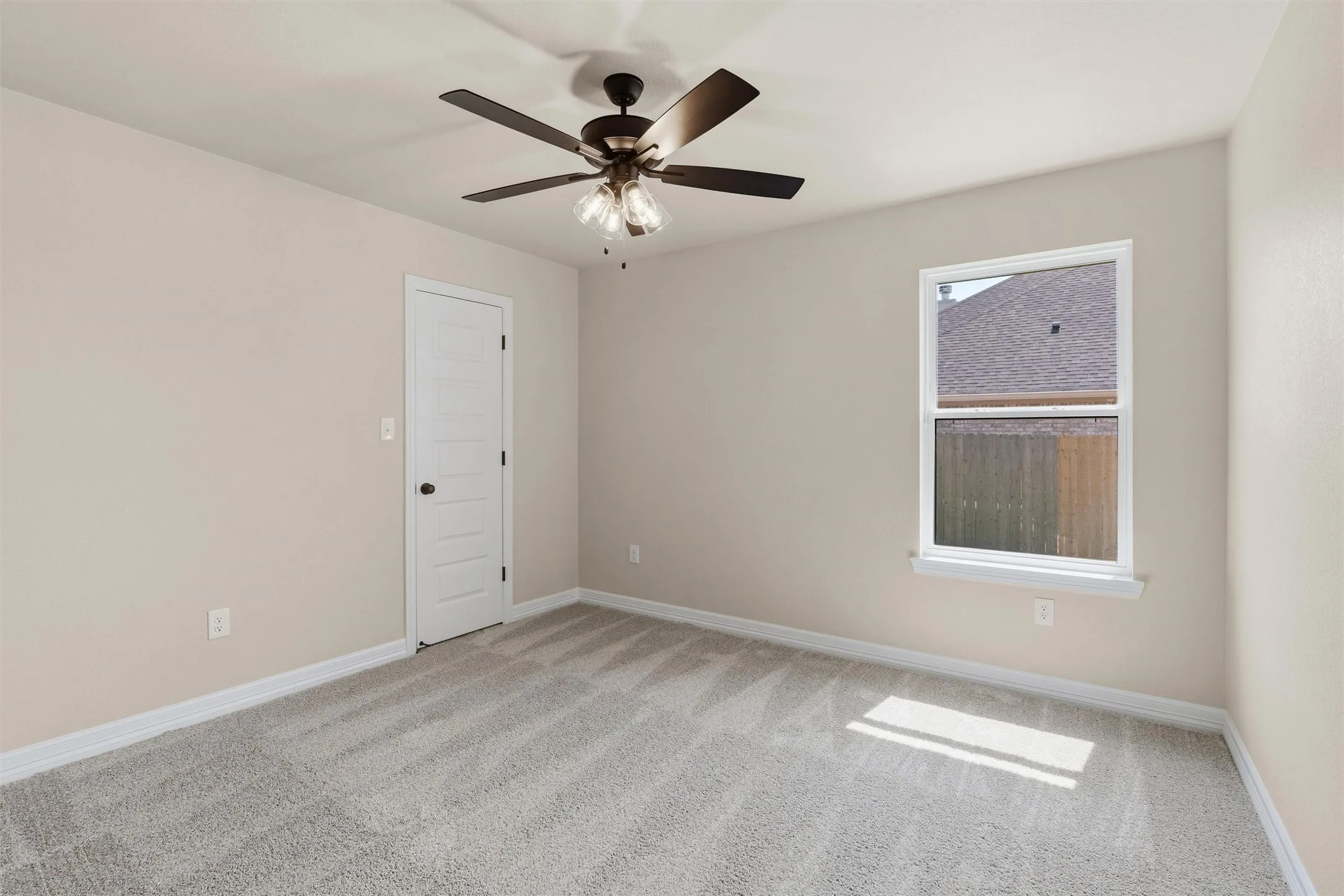 Neutral painted walls, light gray carpet flooring, white trim, white paneled door, and a ceiling fan with light fixture