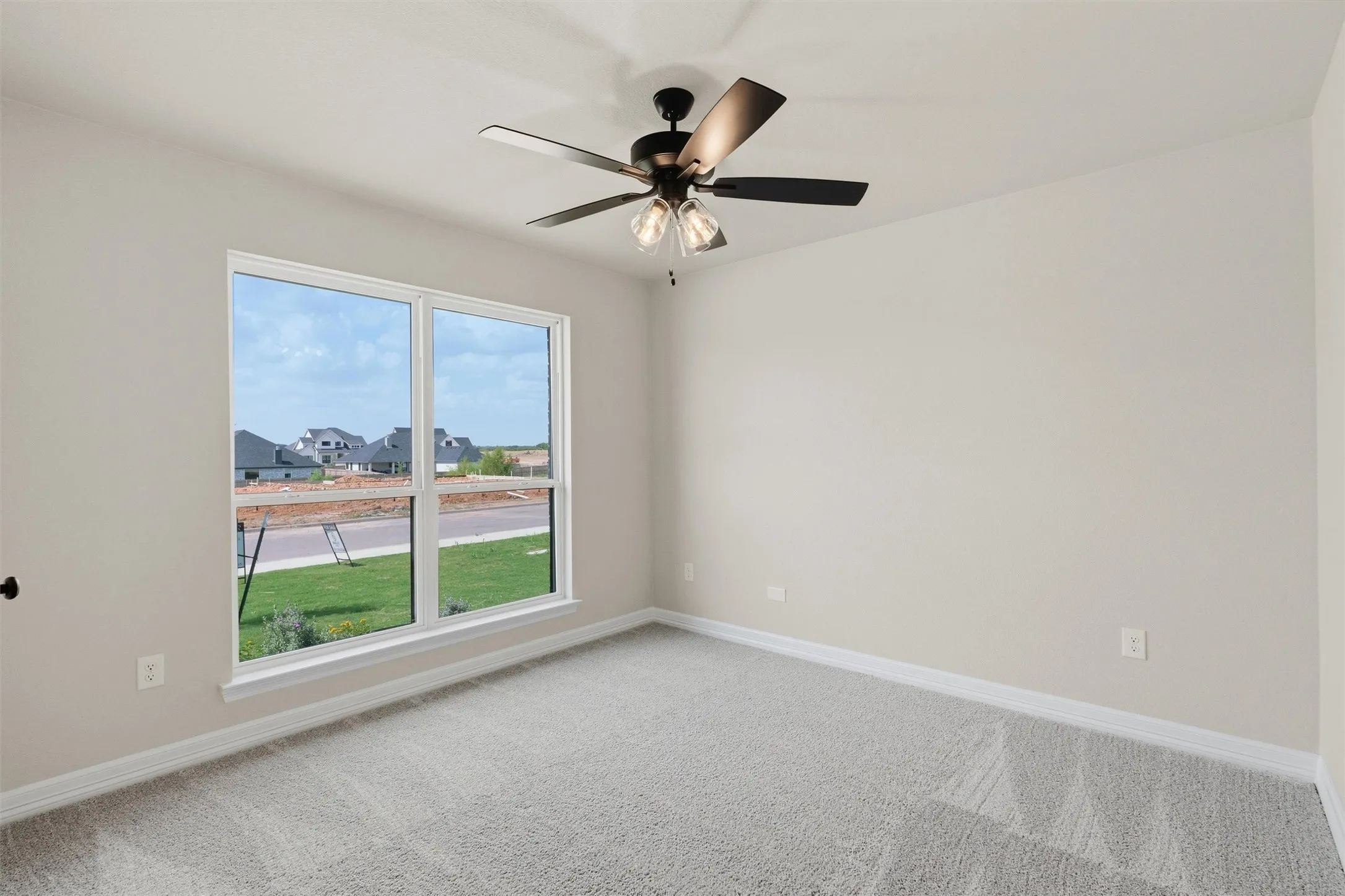 Neutral wall tones, gray carpeting, and a ceiling fan with integrated lighting