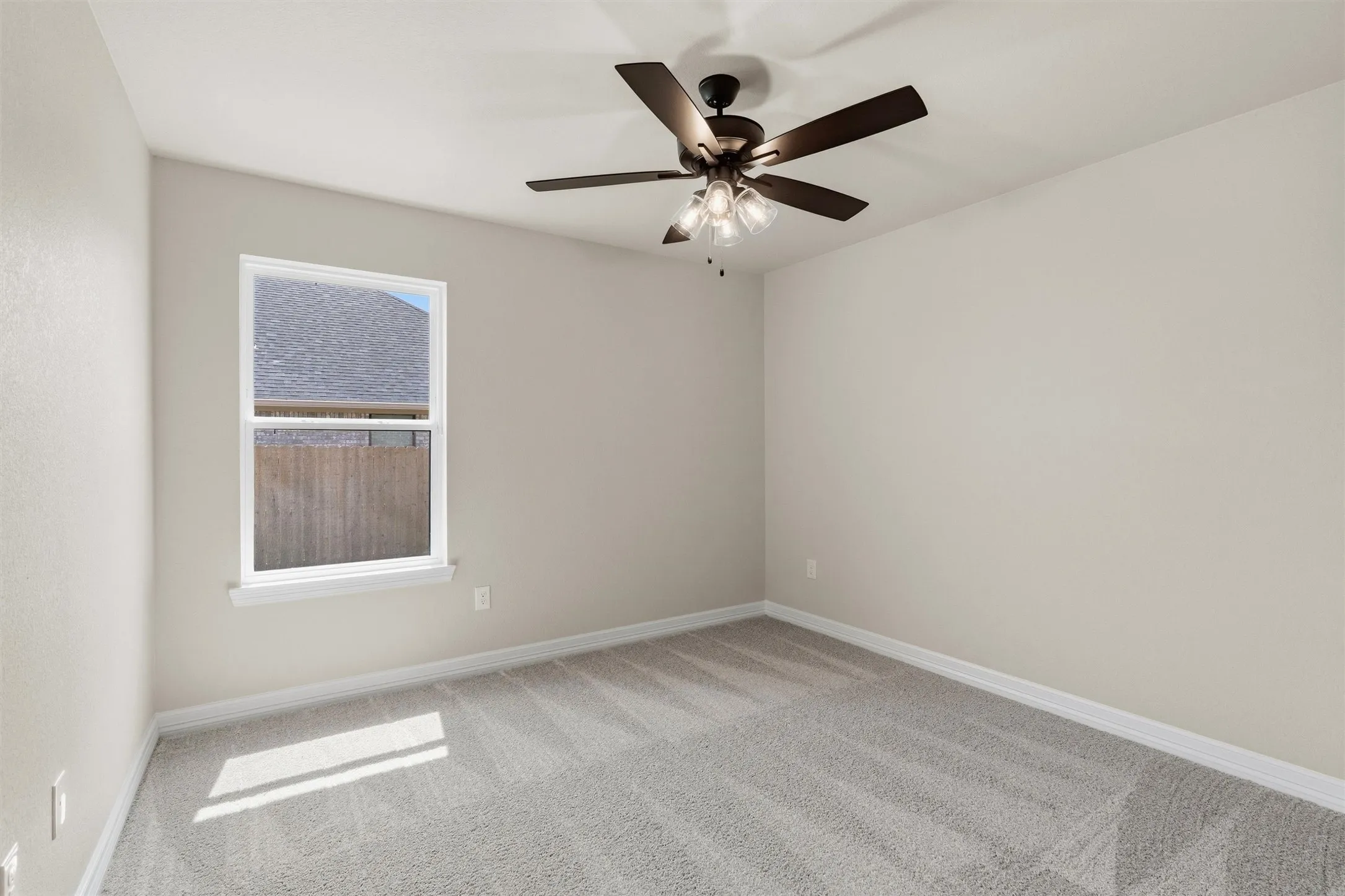 Window with white trim, wall-to-wall carpeting, ceiling fan with light fixture, and painted walls