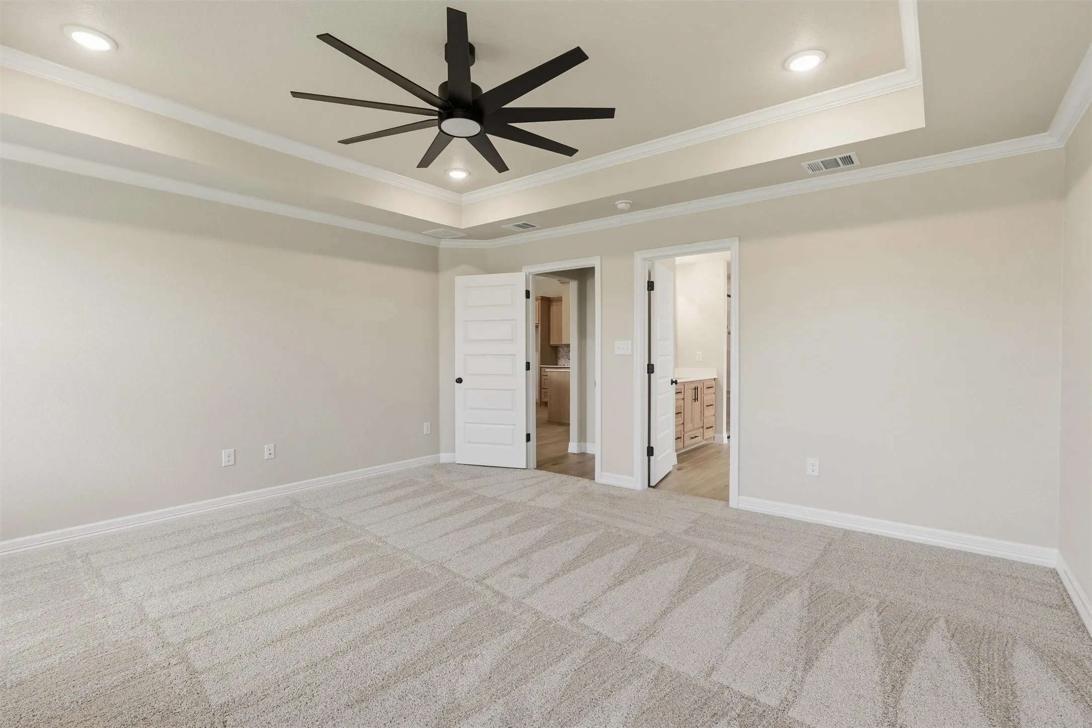 Tray ceiling with recessed lighting, large black ceiling fan, patterned carpet, and paneled interior doors