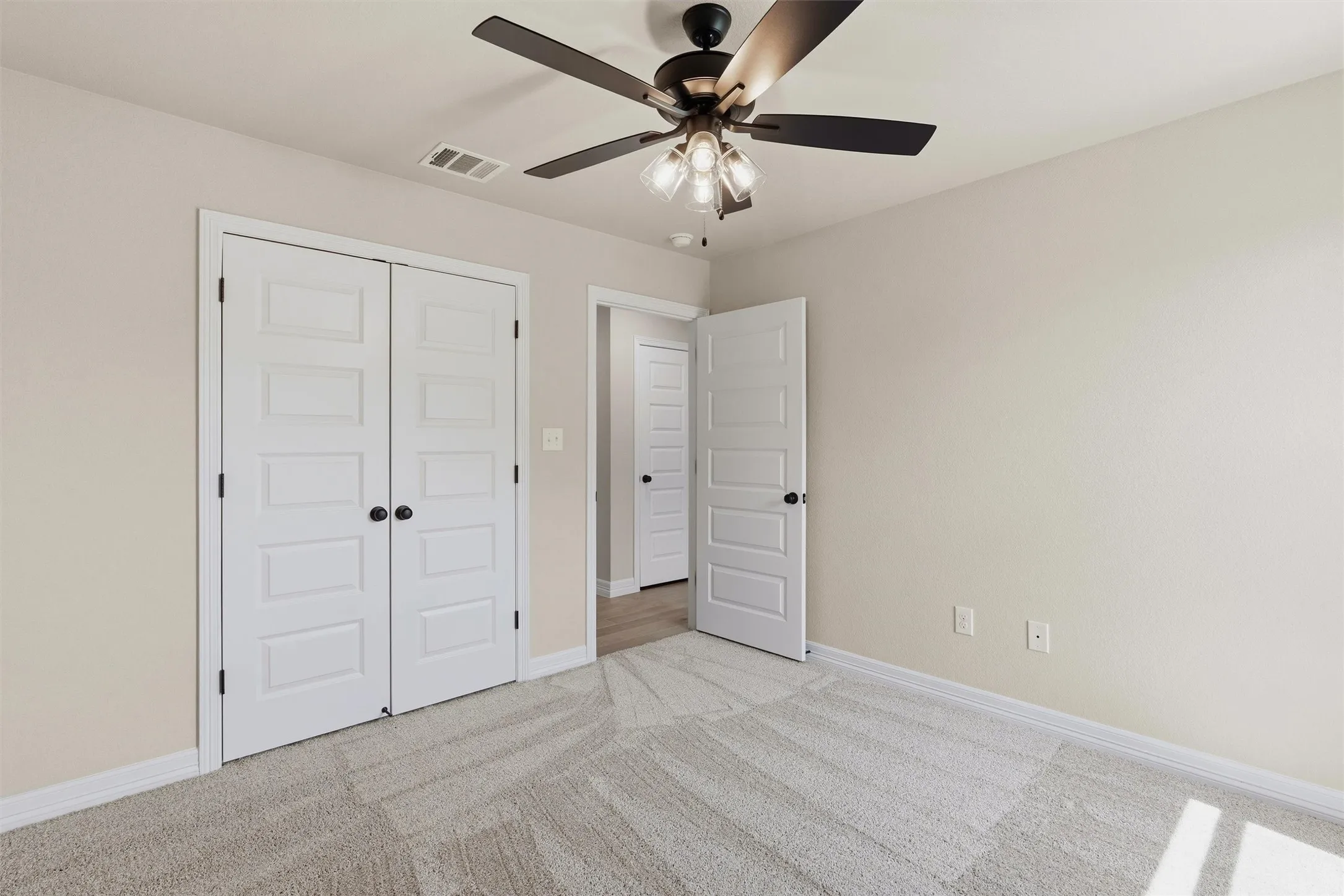 Neutral wall tones, ceiling fan with integrated lighting, paneled doors, and carpet flooring
