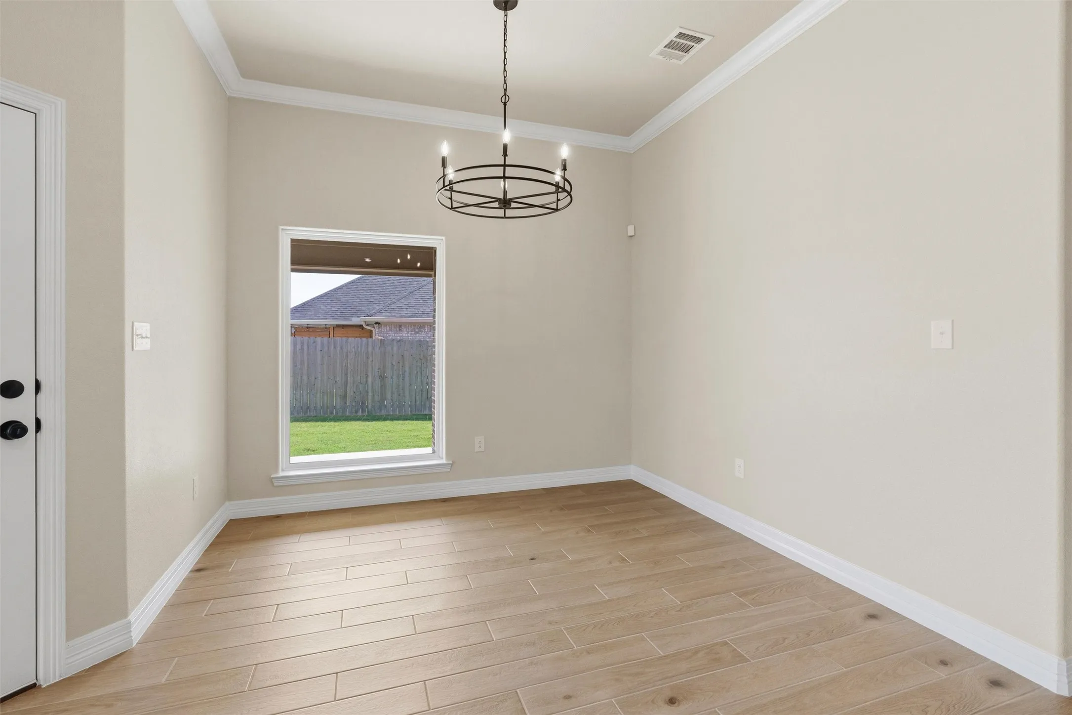 Light-toned walls with crown molding, wood-finish flooring, and a contemporary chandelier