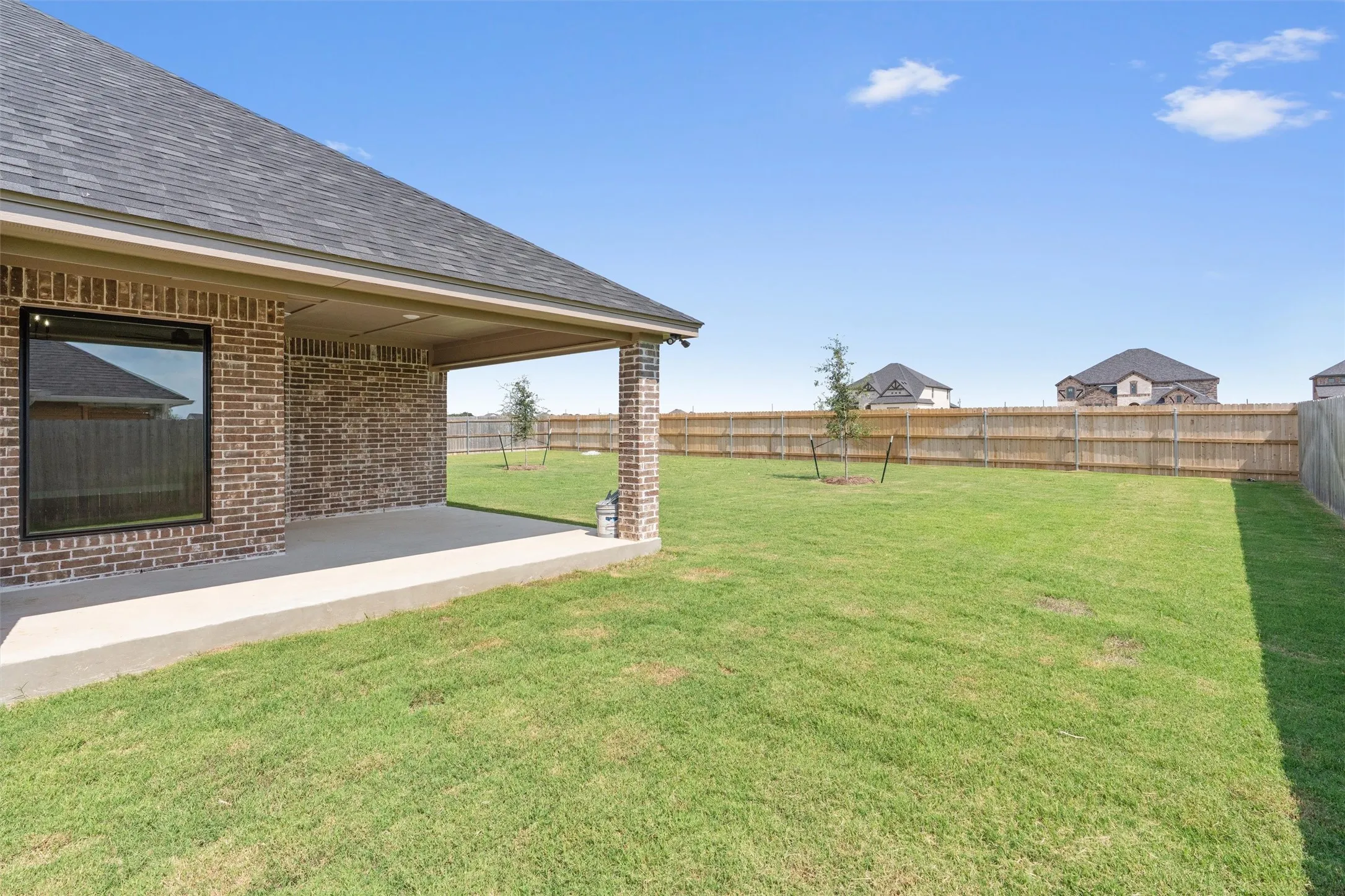 Rear exterior with a covered patio, brick columns, and a fully fenced yard