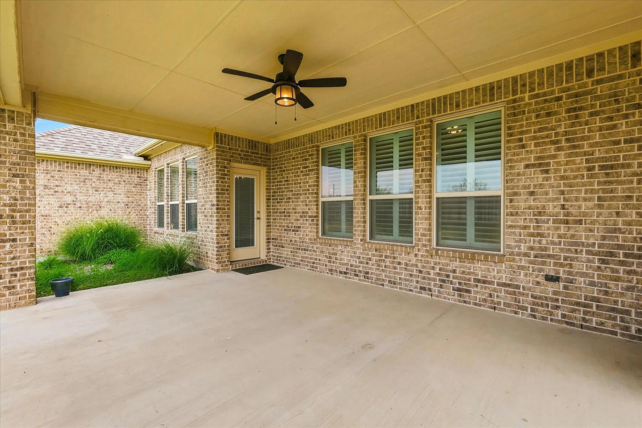 Huge covered back patio with ceiling fan and access to dining area as well as primary suite.