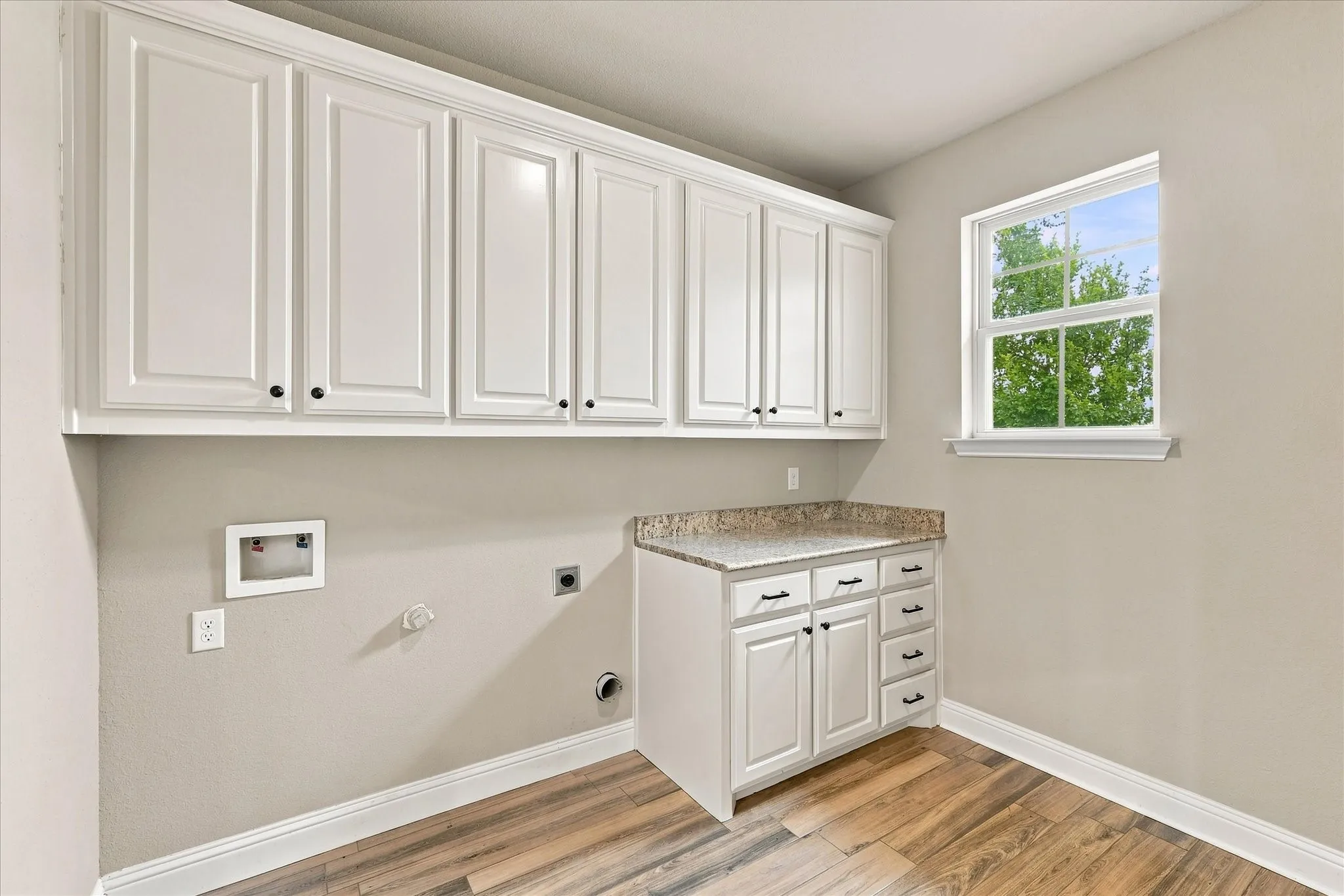 Spacious laundry room with tons of cabinet storage and additional space for storage to the right of the room. Entrance to garage on the left out of frame.
