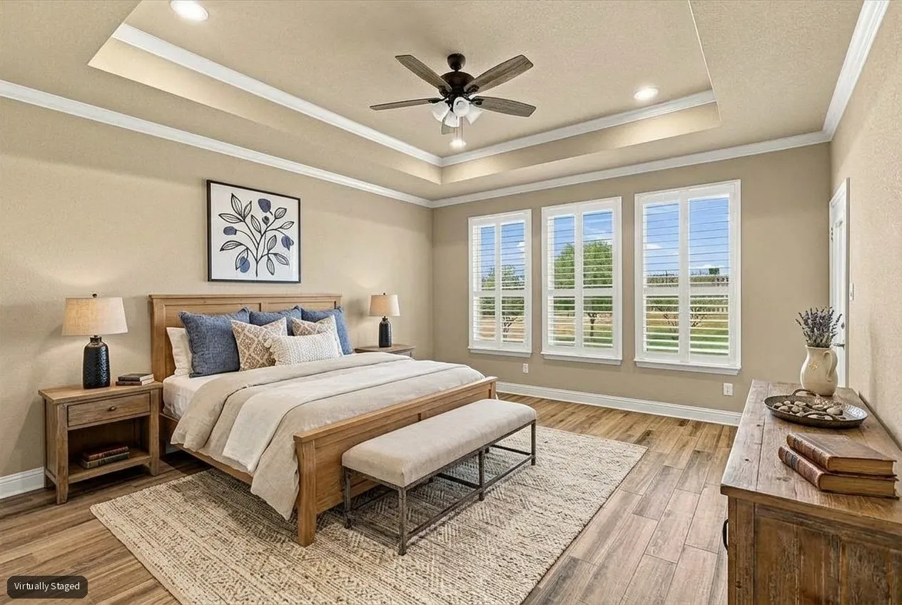 Virtually Staged primary bedrom with tray ceiling and windows overlooking backyard.