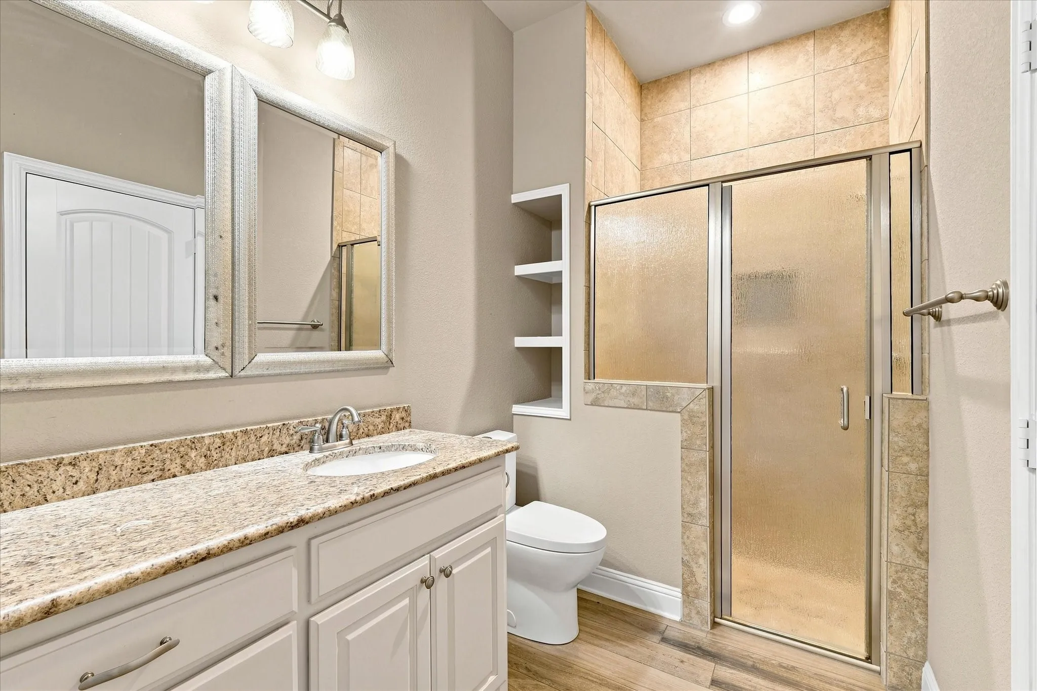 Hall bathroom with tons of counter space, built-in shelves, and walk-in shower with privacy glass.