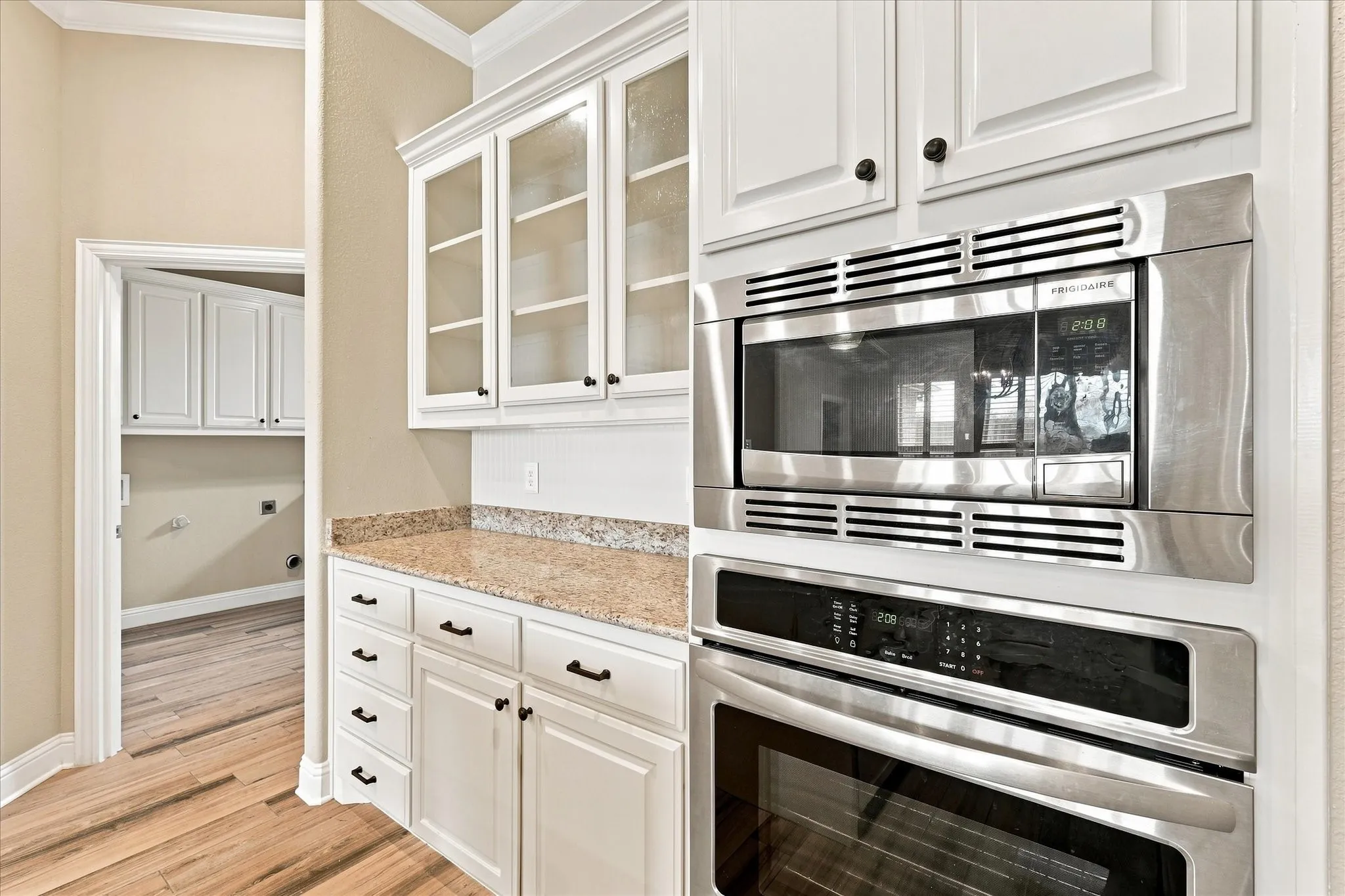 Built in stainless steal microwave above built in oven and a sweet coffee bar with glass front cabinetry.