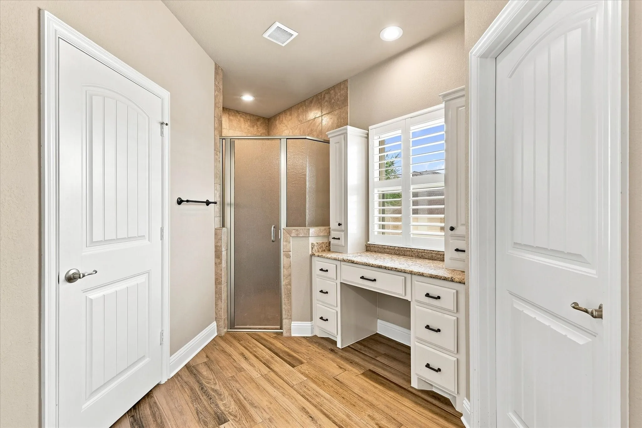 Walk-in shower, walk-in closet, private toilet room, and a bathroom vanity with window view for natural light and personal care.
