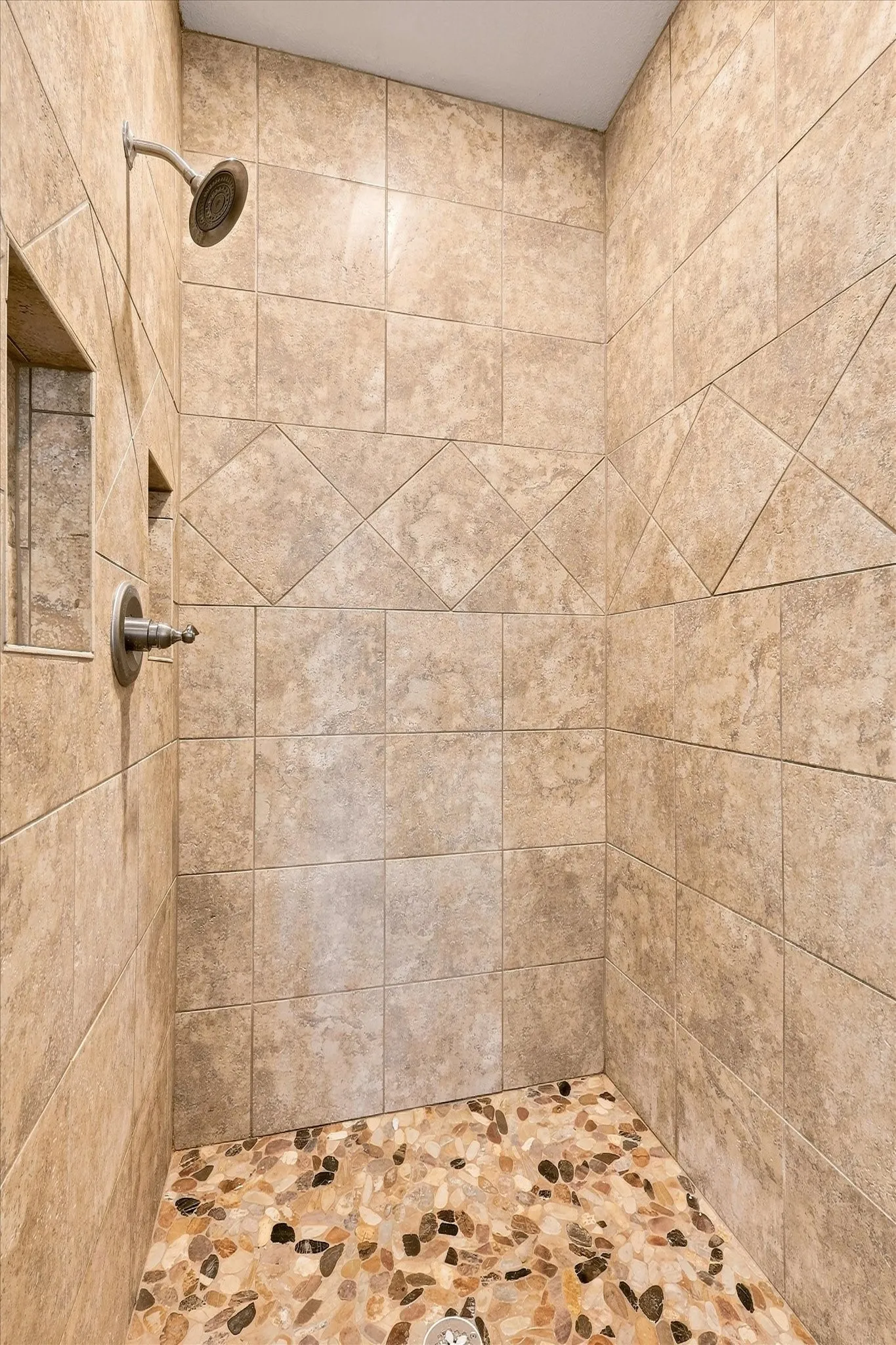 Large walk-in shower with river-stone floorpan and built in niche.