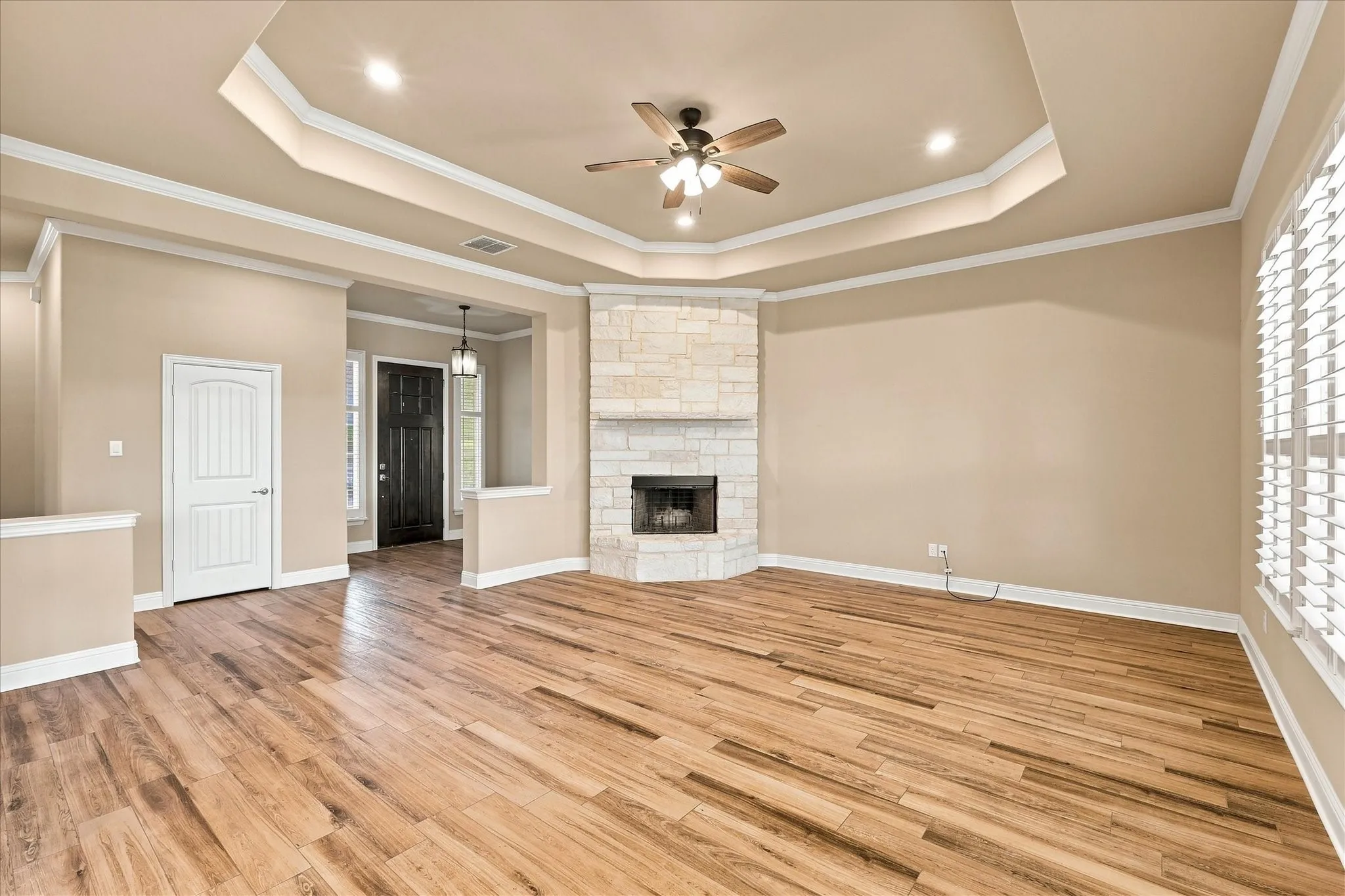 Grand living room with tray ceiling and a wood-burning stone fireplace.